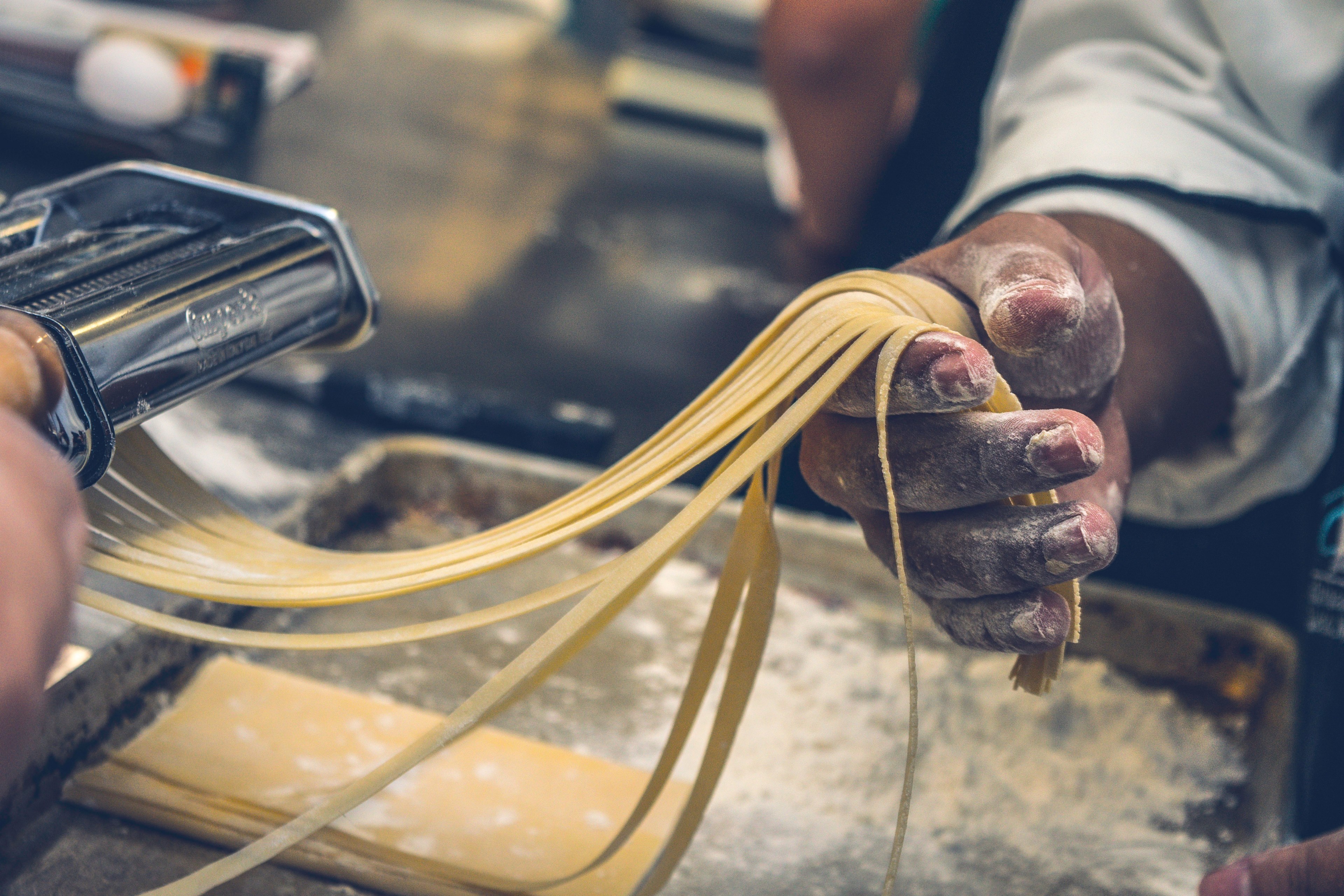 a chef holding long strands of pasta coming out of a machine, making pasta 4k, HD Wallpaper