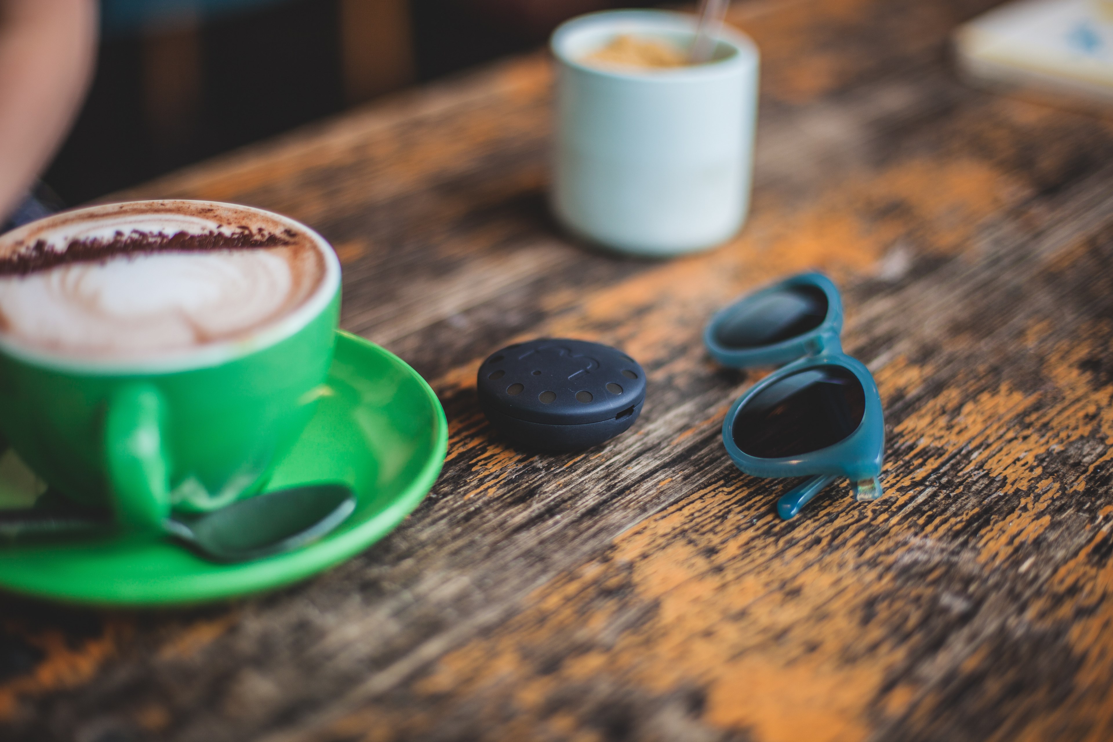 a blurry shot of a latte in a green cup next to small sunglasses on worn out wooden surface, green latte cup and sunglasses 4k, HD Wallpaper