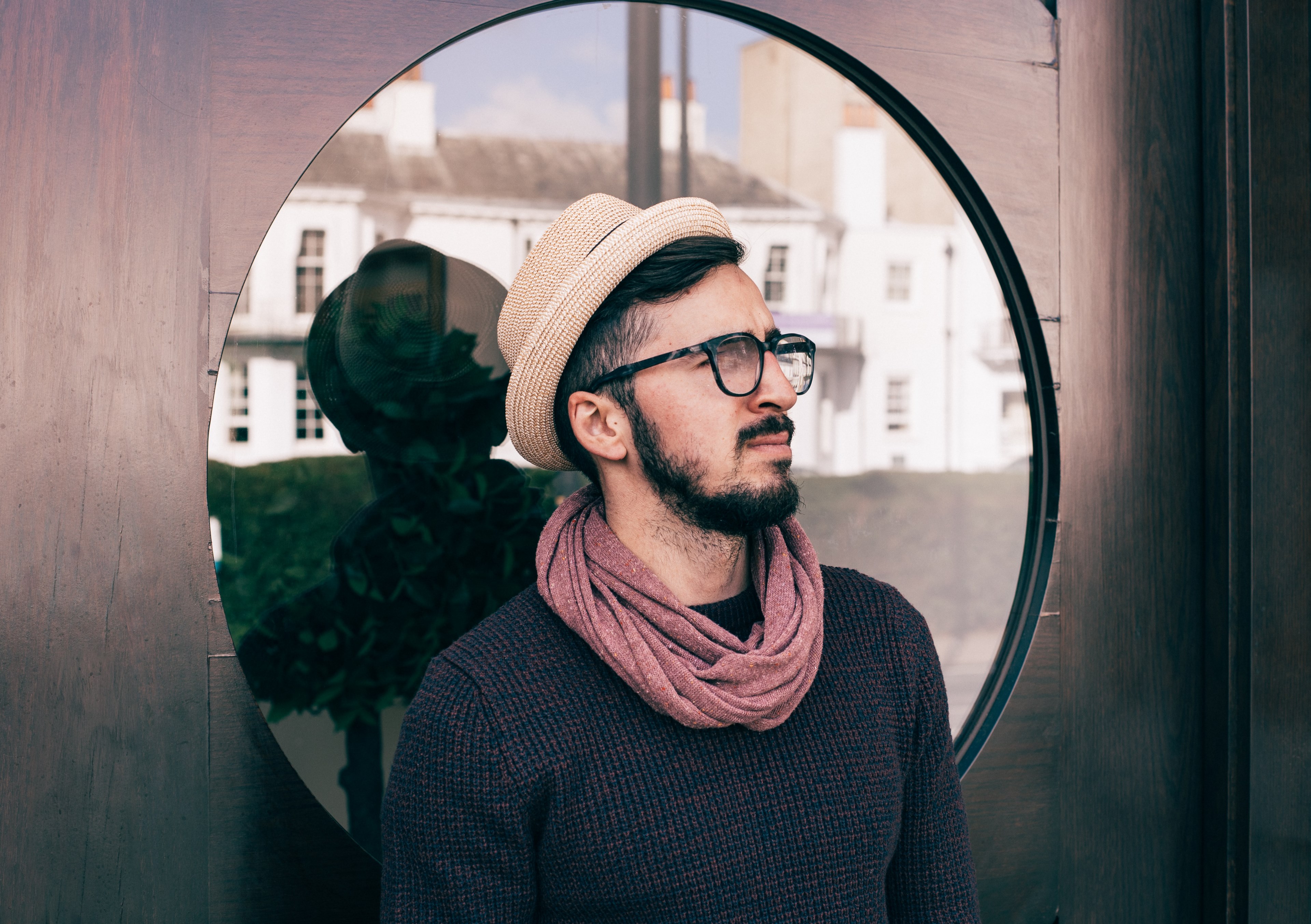 a man wearing a hat scarf and glasses stands in front of a window in richmond, _man with circular window 4k, HD Wallpaper