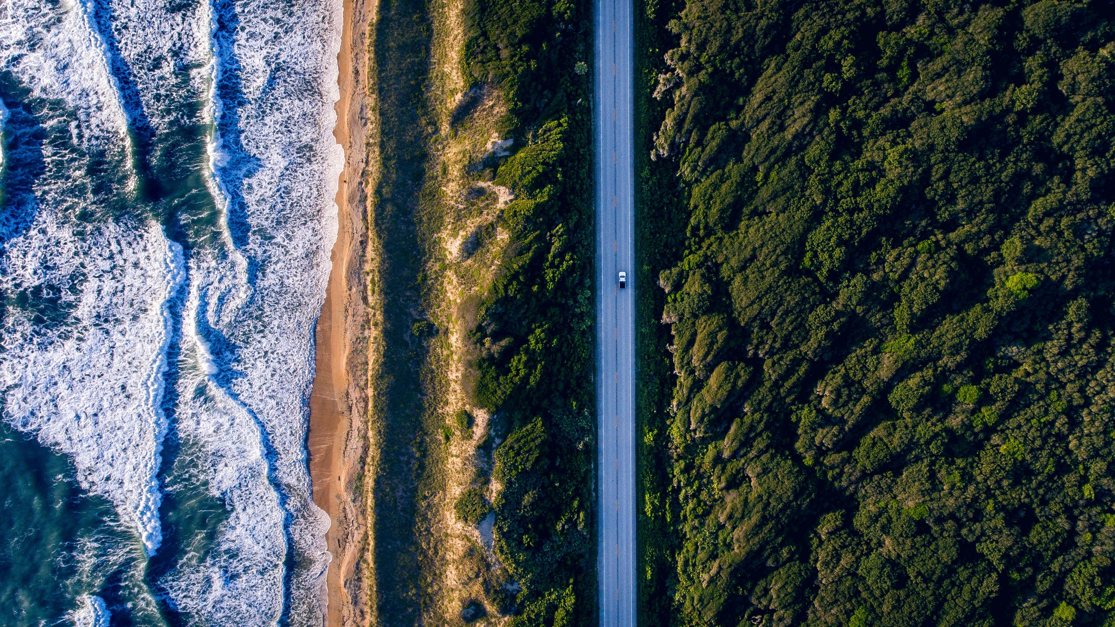 drone aerial view of the car on a straight seaside road between the forest and the rough sea in ponte vedra beach, water on fire 4k, HD Wallpaper
