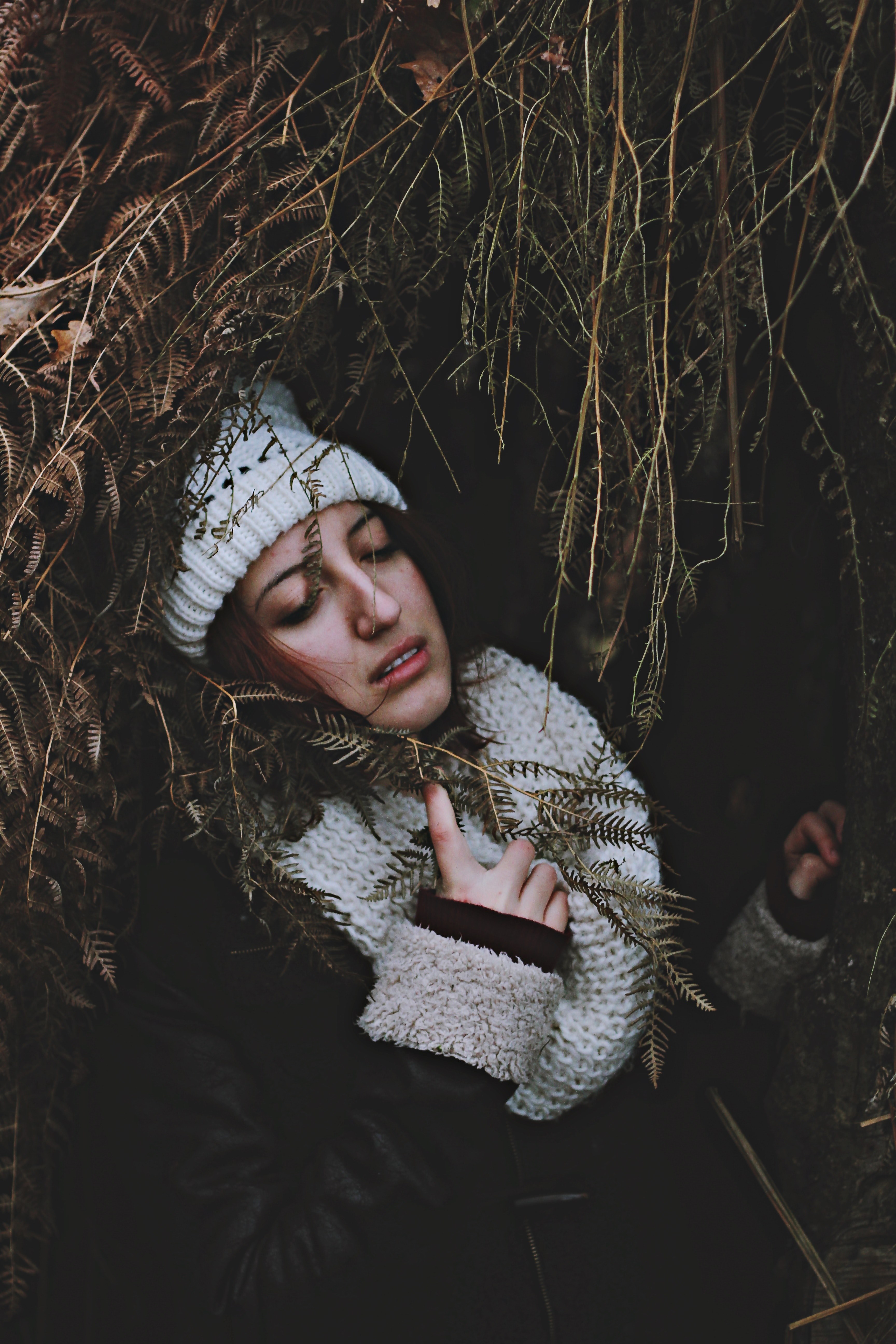 a brunette woman wearing a circle scarf and knit hat laying in grass in biarritz, woman in dry foliage 4k, Phone HD Wallpaper
