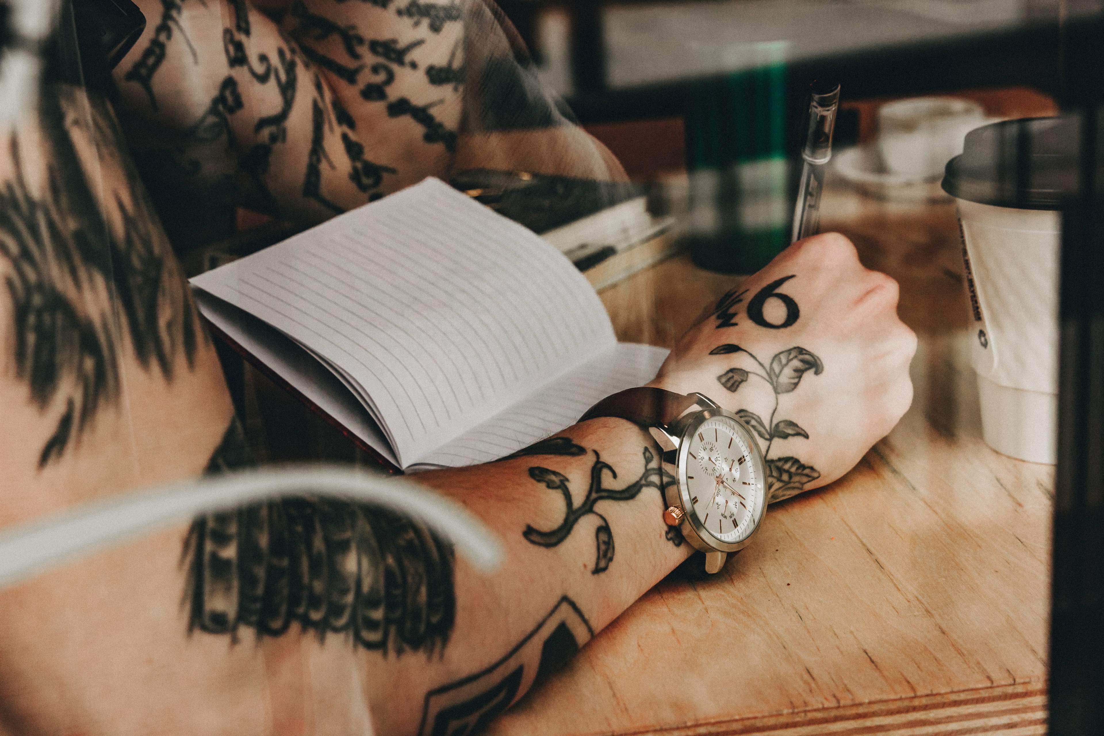 milwaukee man with tattoos wearing wristwatch writing in journal while sitting at cafe, captivated_ 4k, HD Wallpaper