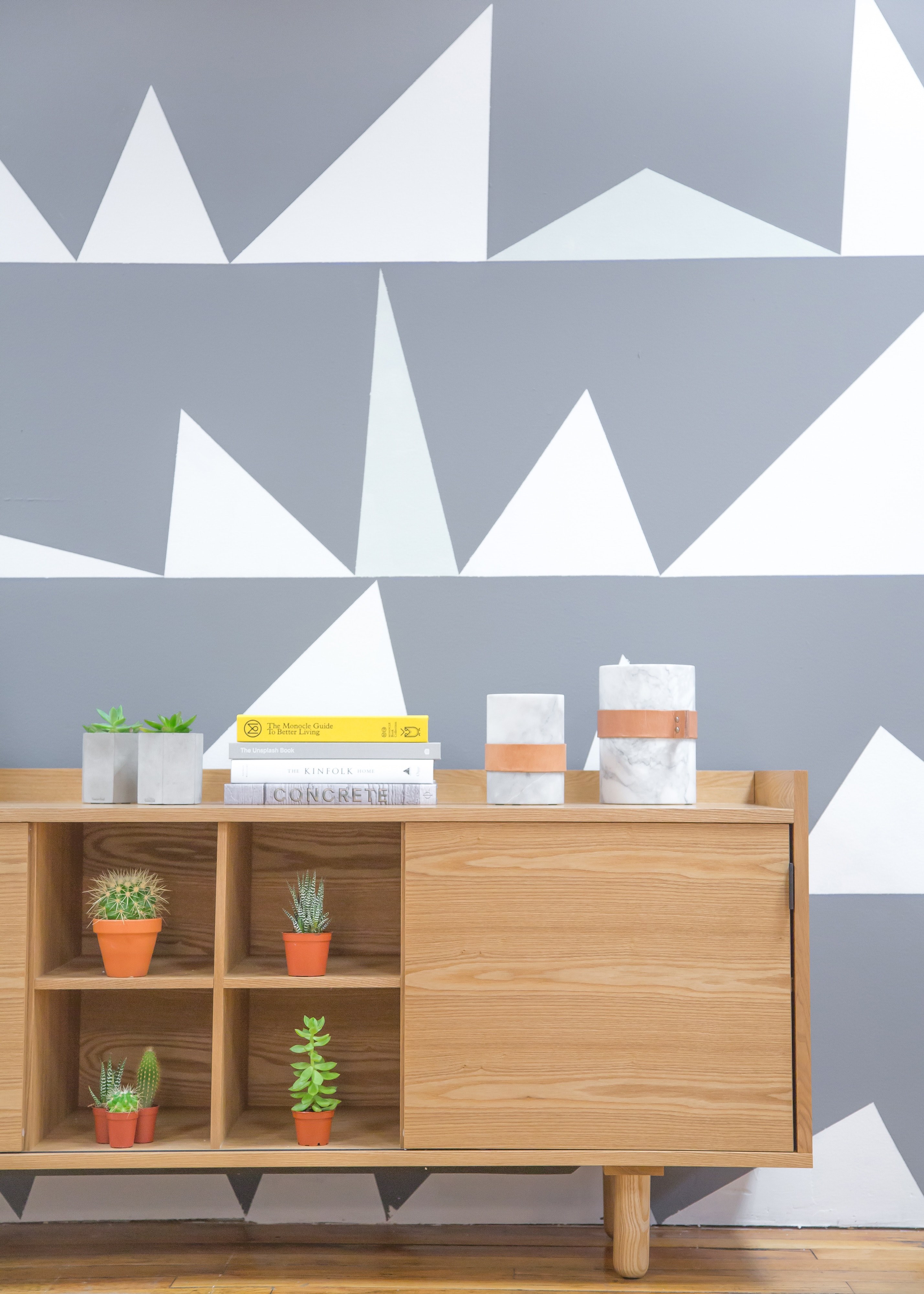 a desk with potted green plants and a stack of books near a wall with a geometric pattern, desk at a geometric wall 4k, Phone HD Wallpaper