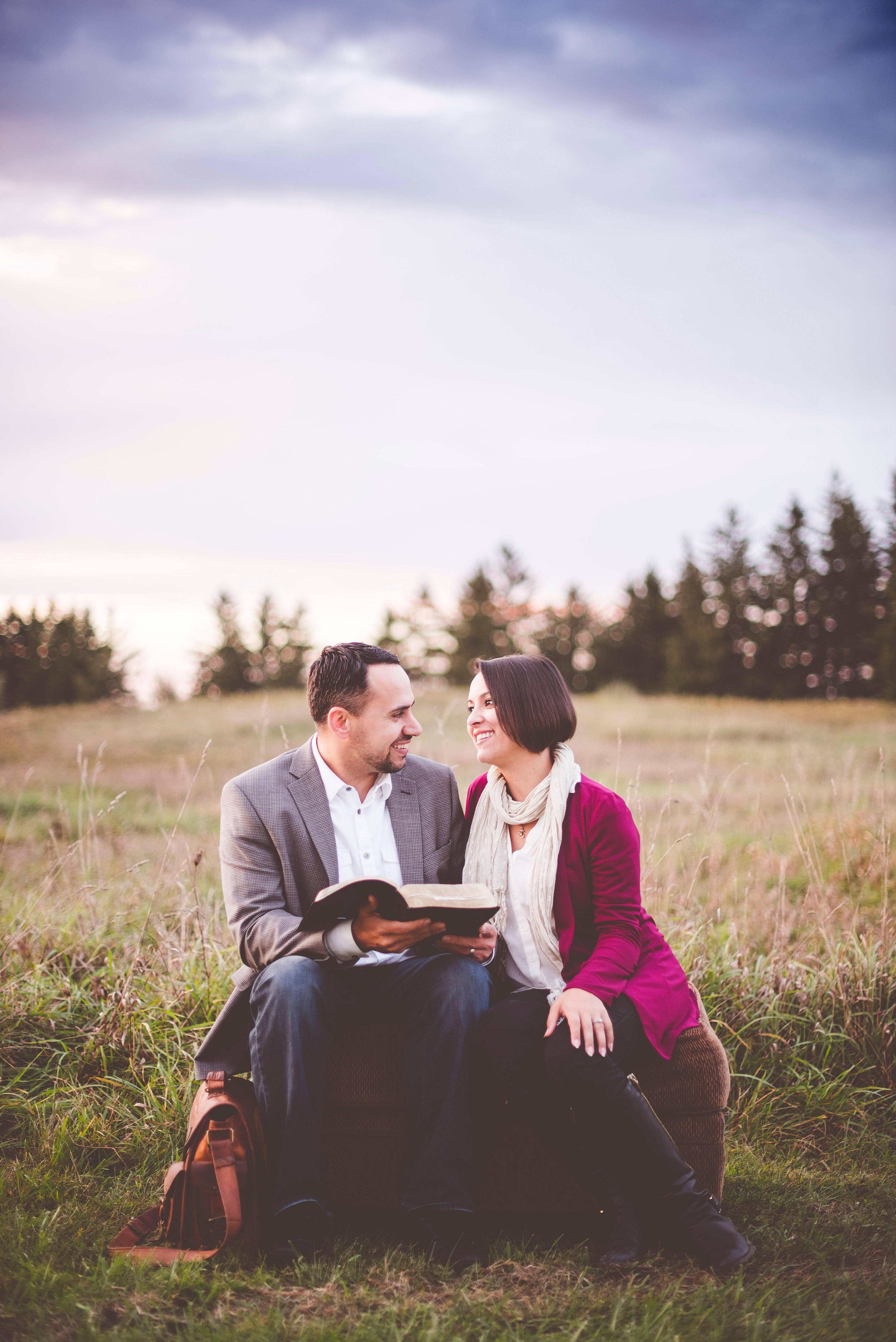 a married couple sits looking at each other on an ottoman outdoors_ hes holding a book, book couple on ottoman 4k, Phone HD Wallpaper