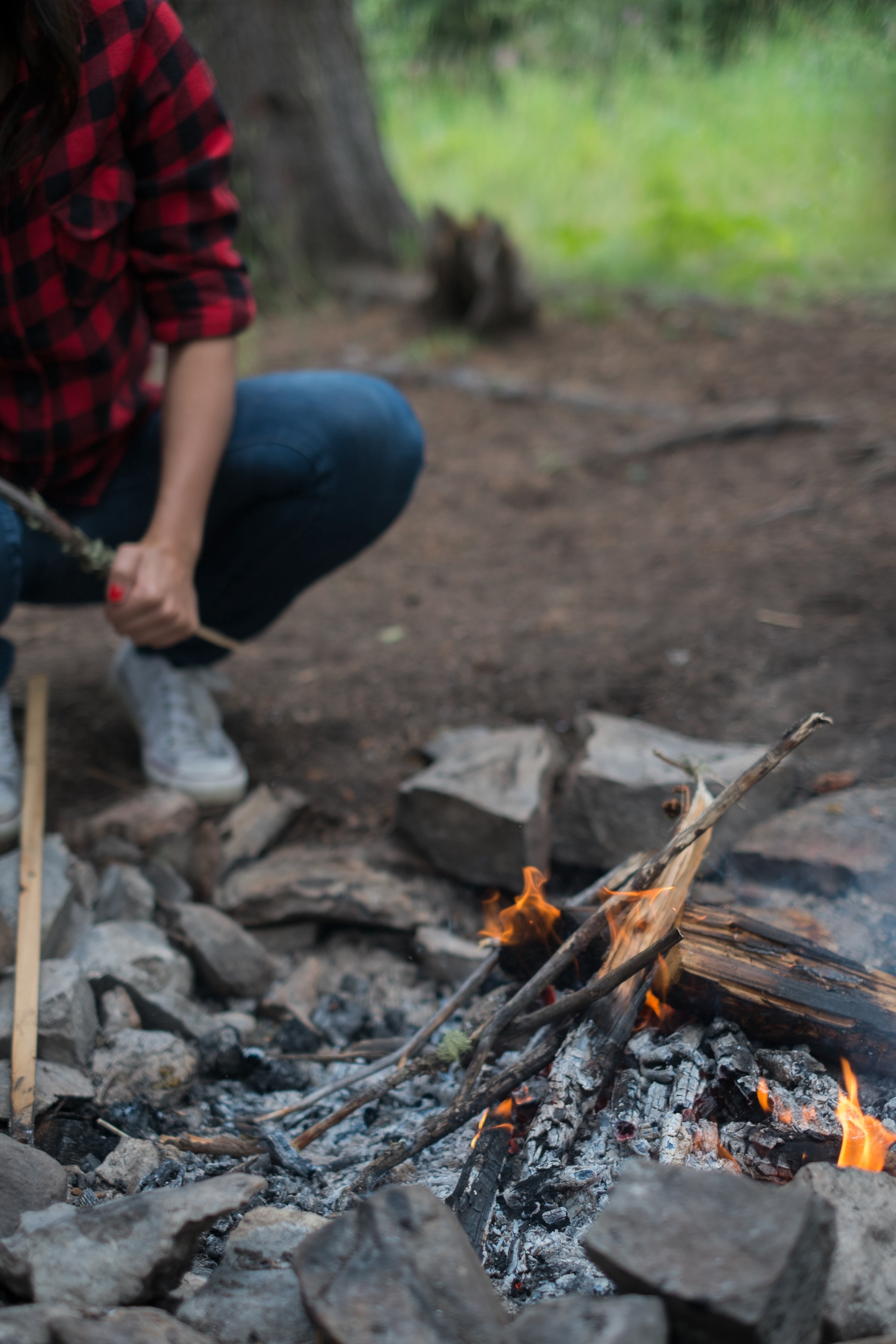 a camper wearing flannel and jean tending to a fire while camping, fire during camping 4k, Phone HD Wallpaper