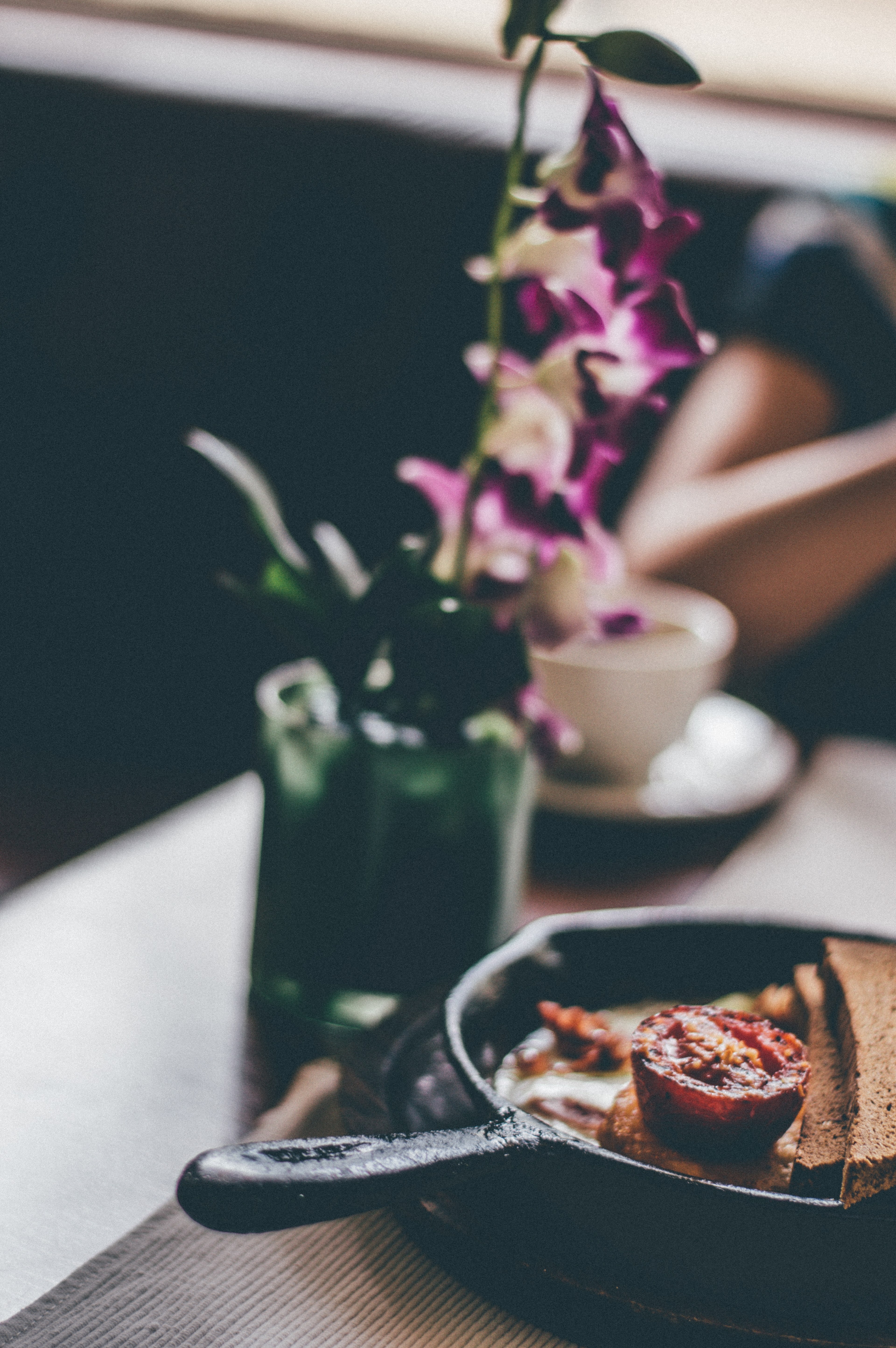 a blurry shot of a skillet with a fried tomato and bread next to a flower vase on a table, flowery breakfast 4k, Phone HD Wallpaper