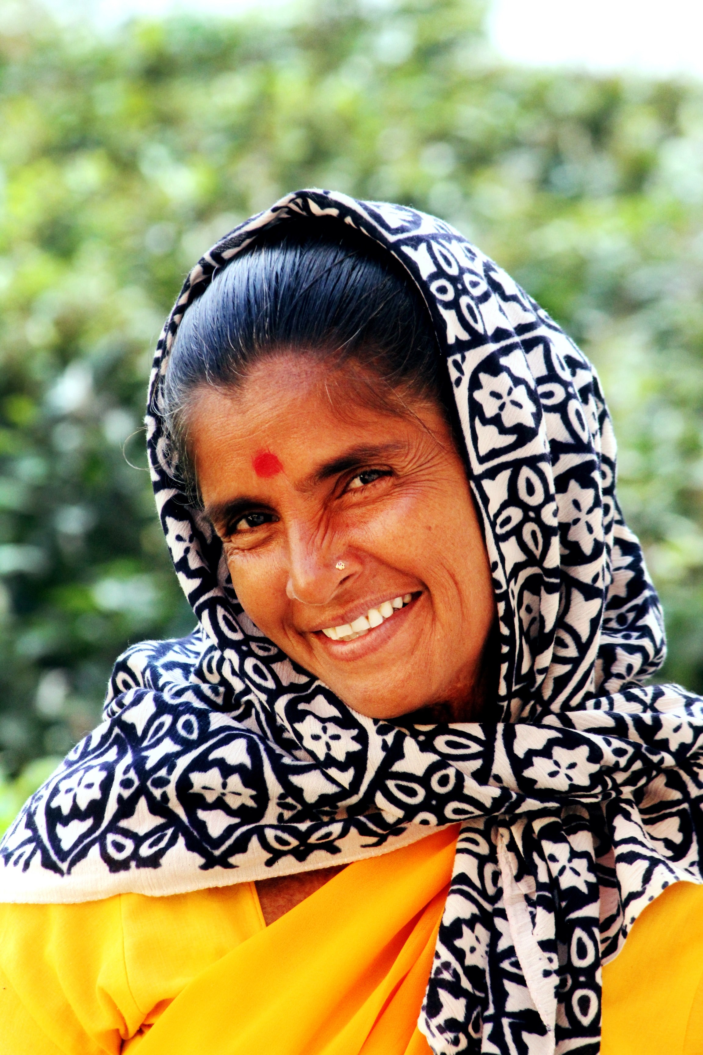 a woman with black hair a loose head scarf and yellow top smiles she has a bindi on her forehead and a small piercing in her nostril, _woman with bindi smiles 4k, Phone HD Wallpaper