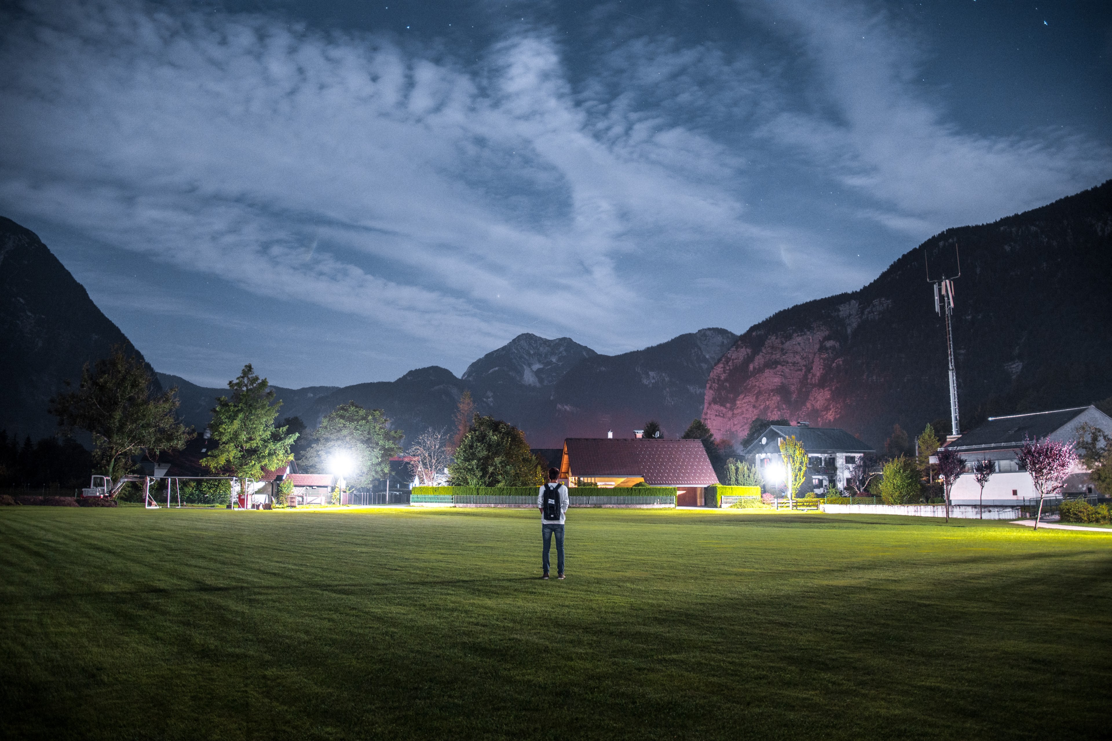 man with a backpack standing on the soccer field in obertraun at night, man standing on the field at night 4k, HD Wallpaper