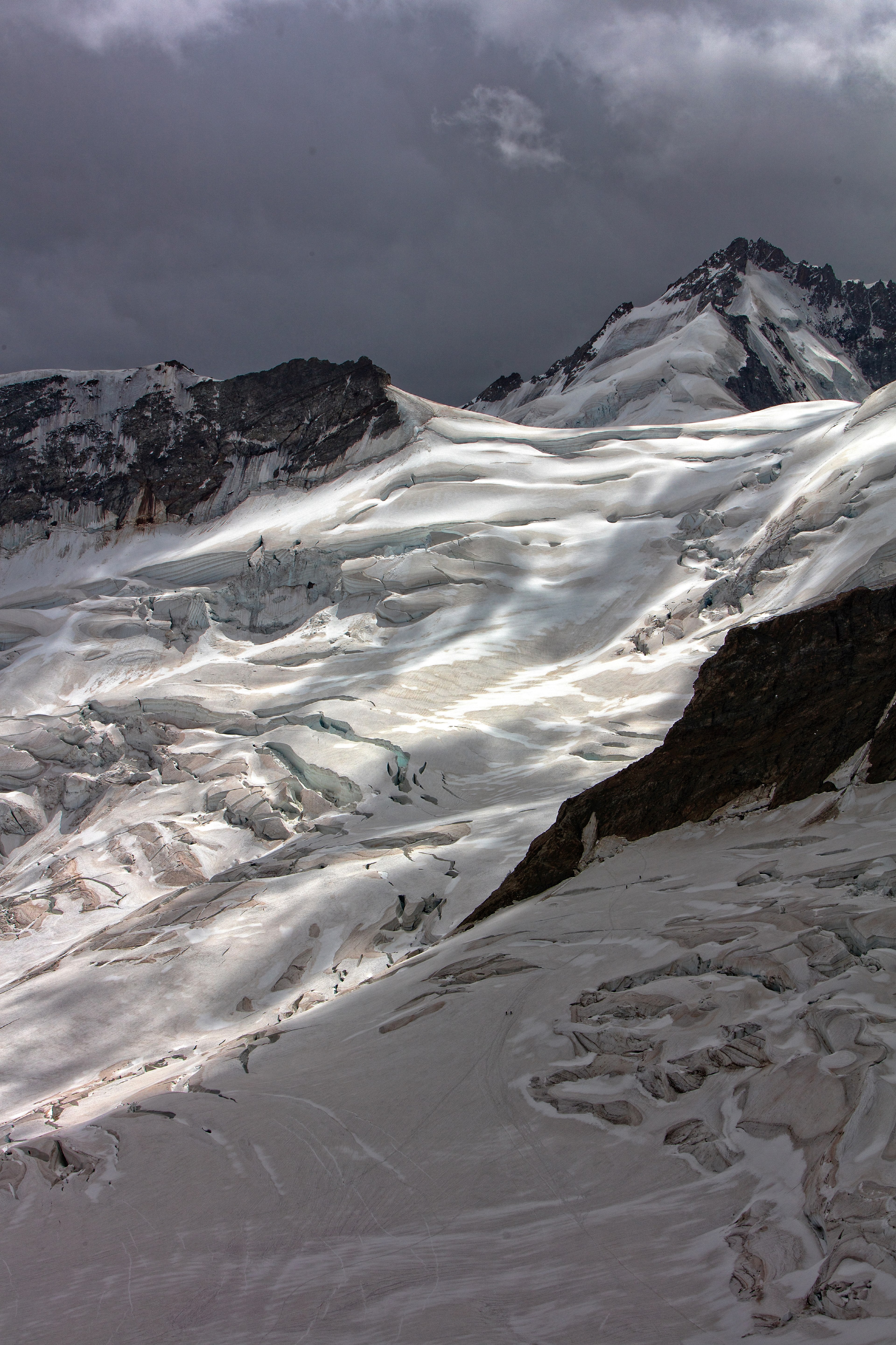 an icy snowy mountain slope under a dark cloudy sky, snow ice and light 4k, Phone HD Wallpaper