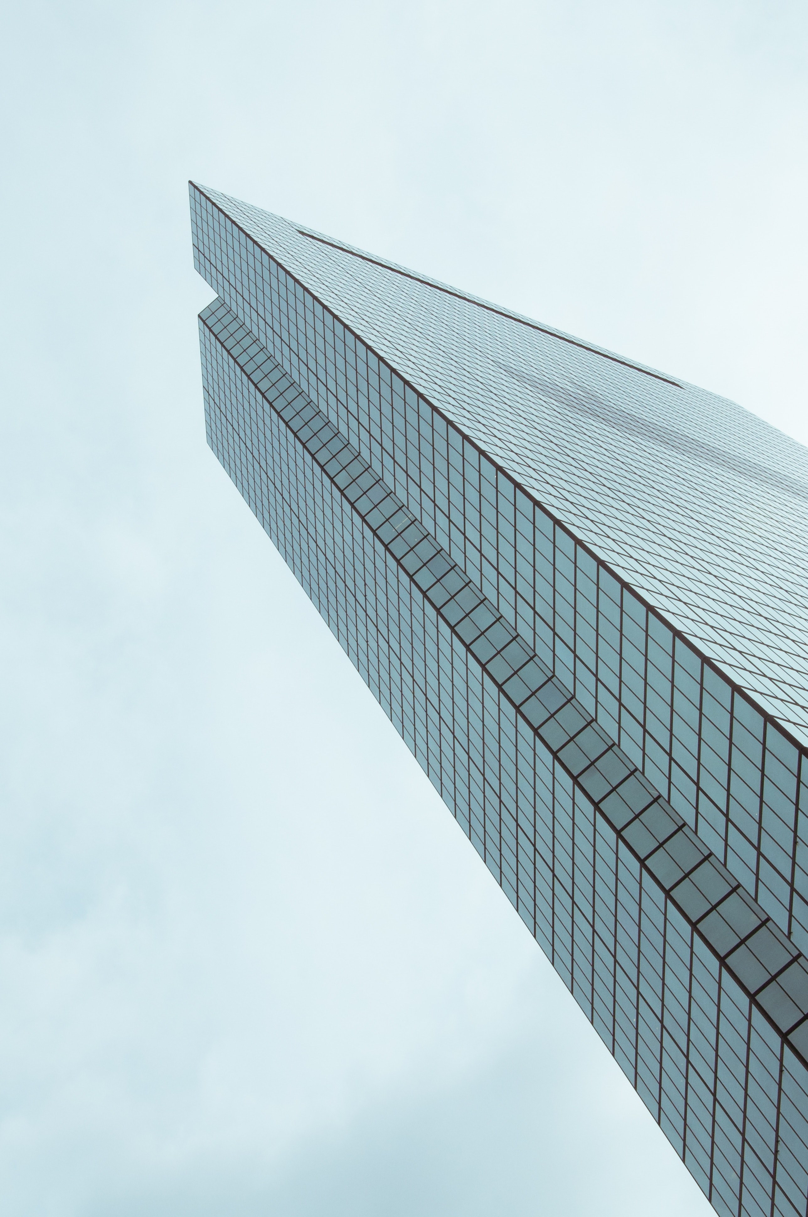 an angular shot of a skyscraper under a cloudy sky, modern skyscraper 4k, Phone HD Wallpaper