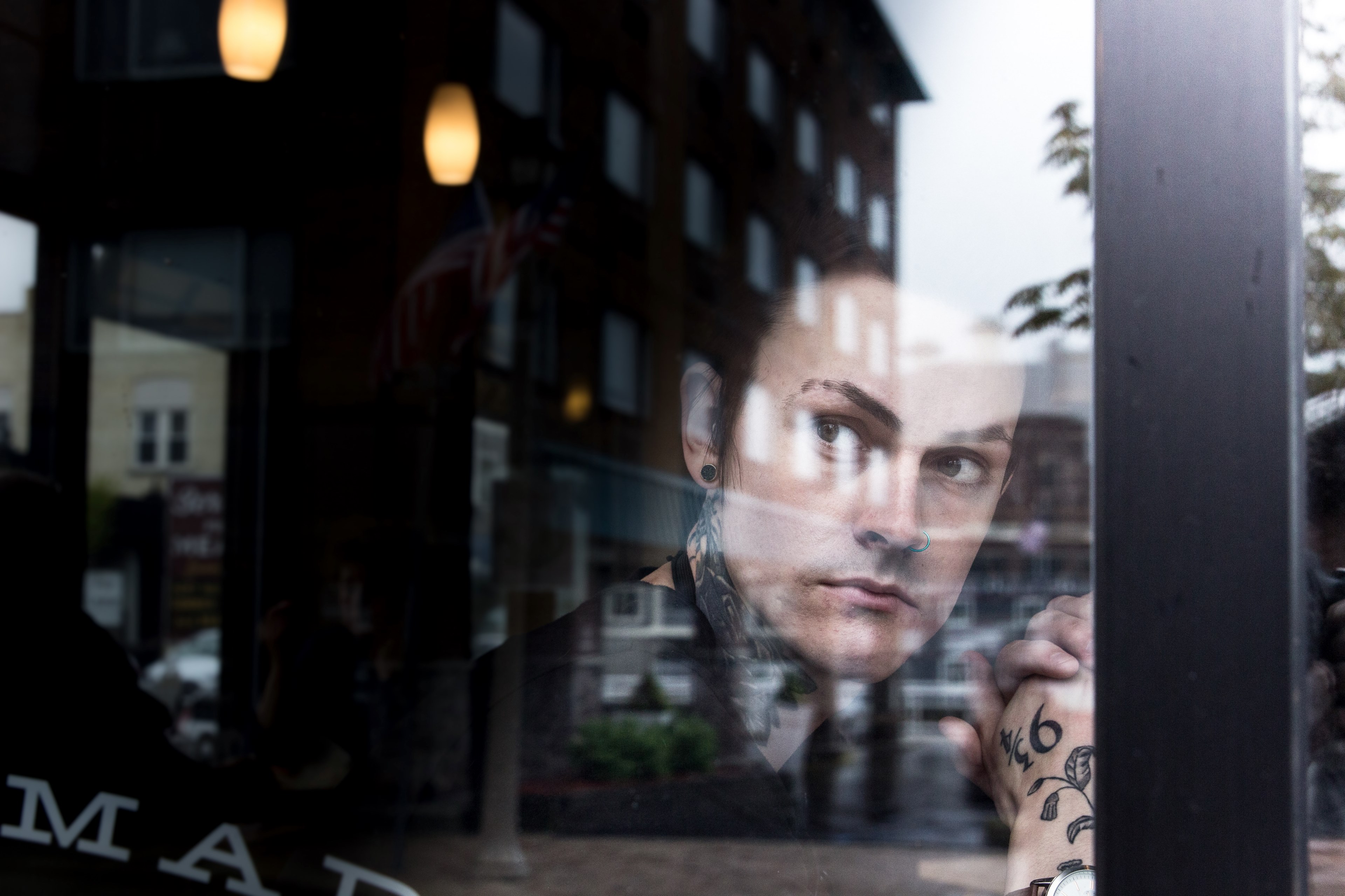 person with tattoos looks out a restaurant window with reflections of buildings, optimistic 4k, HD Wallpaper
