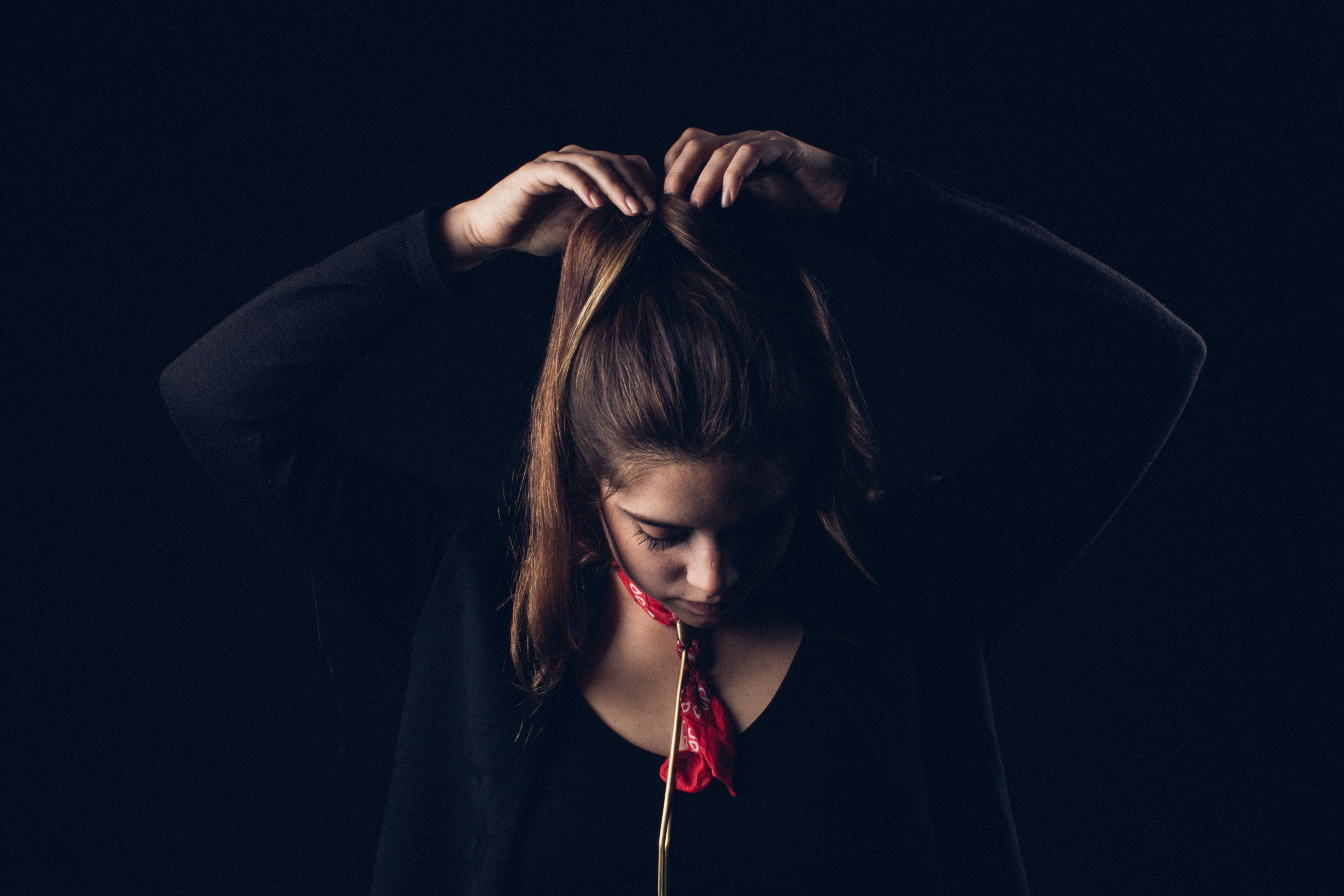 a woman wearing a red bandana and black shirt fixes her ponytail against a black background, woman fixing ponytail 4k, HD Wallpaper