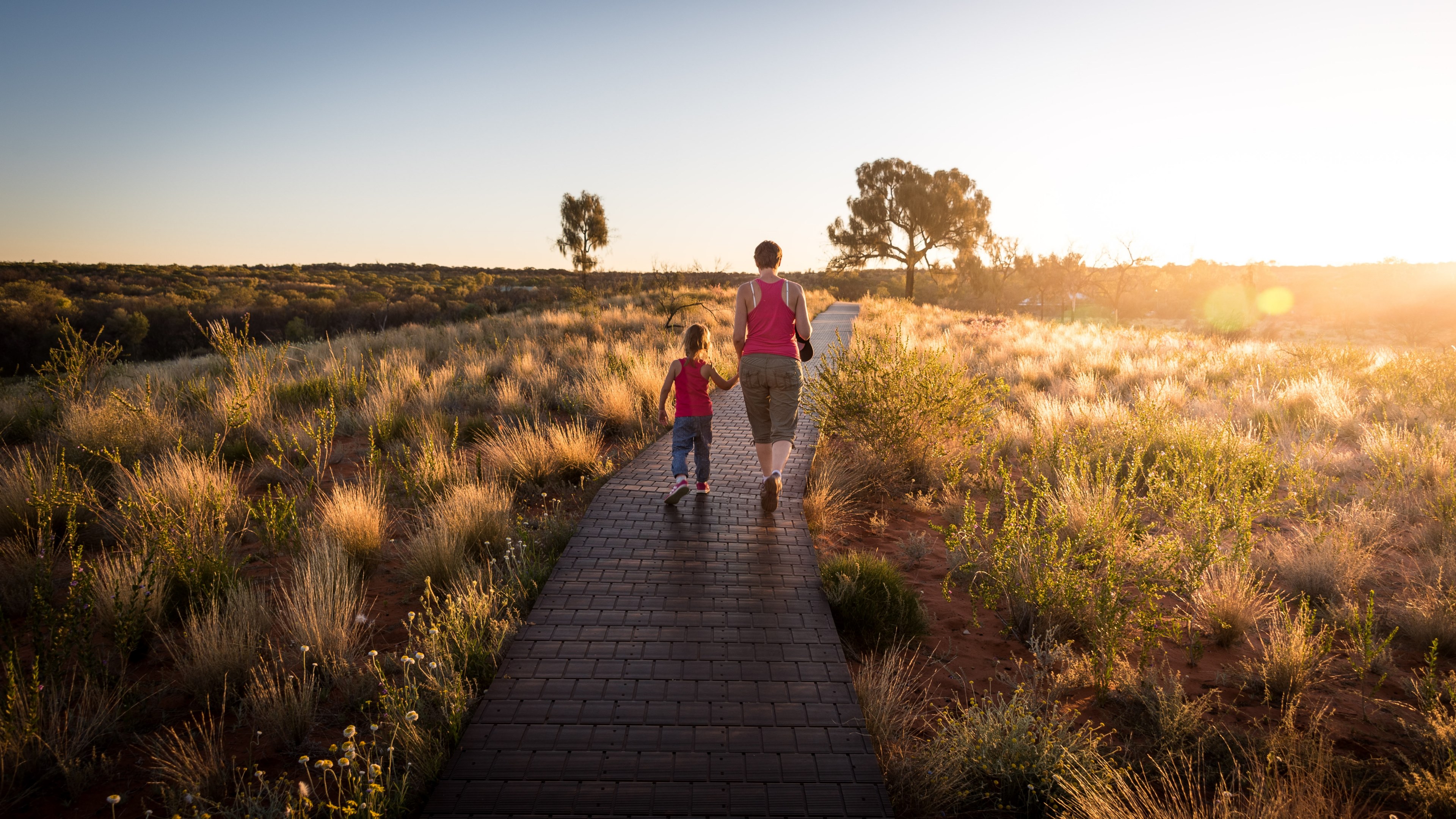 a mom and daughter both wearing pink vest tops walking on a gangway surrounded by grass and foliage in the sunshine, matching tops for mom and daughter 4k, HD Wallpaper