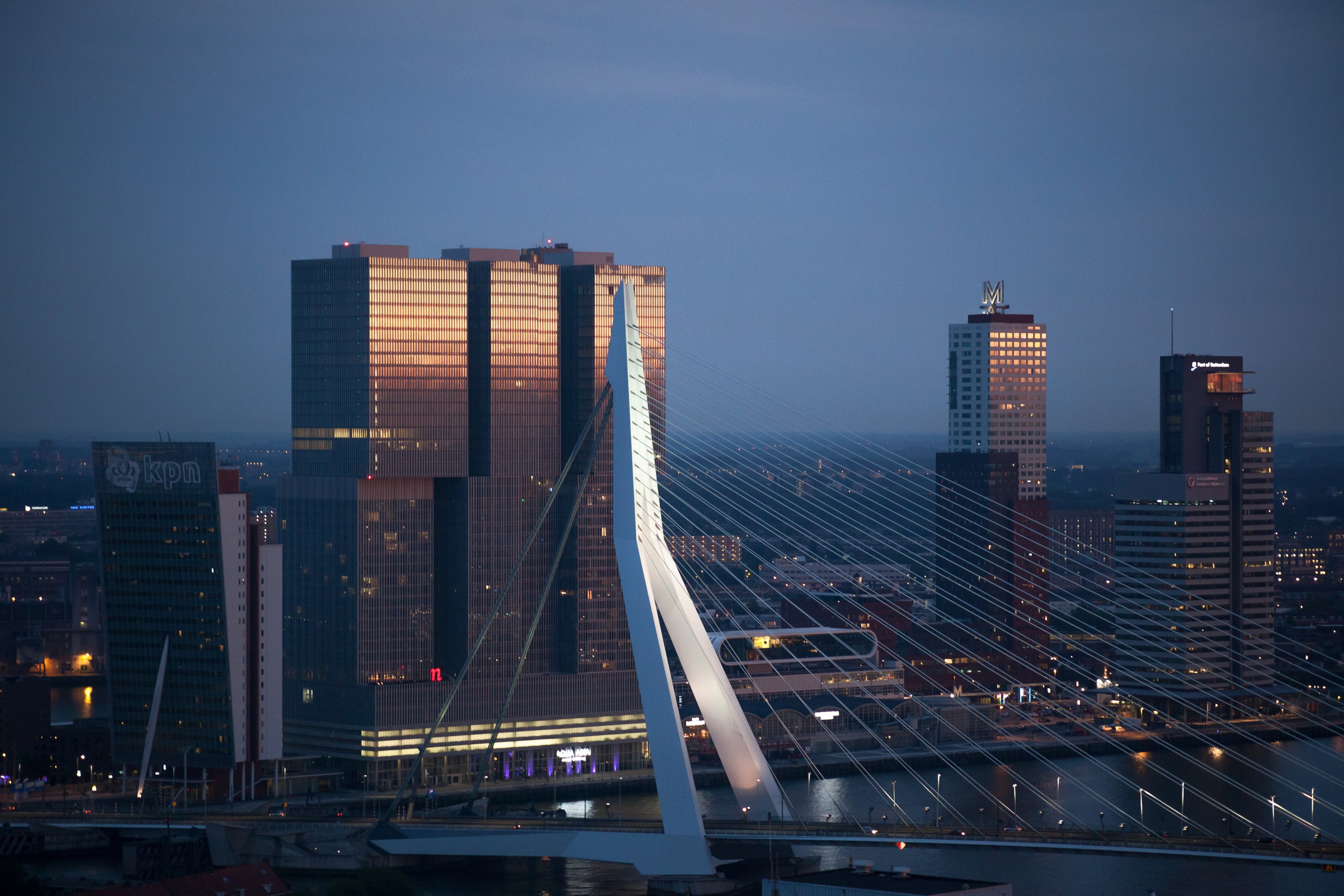 a bridge connecting two shores of a river in rotterdam with high rises on the bank, erasmus bridge at sunset 4k, HD Wallpaper