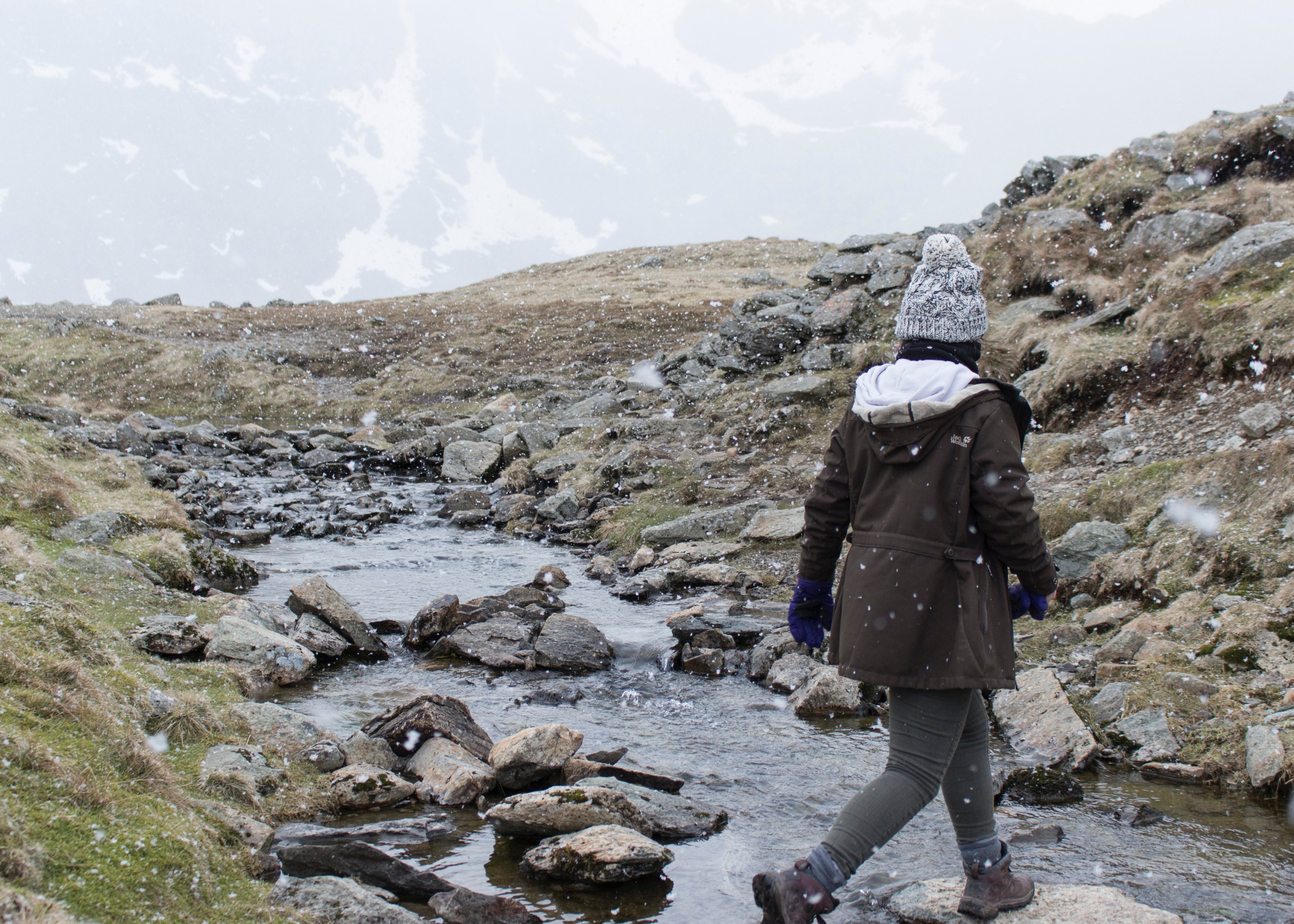 woman hiking across a stony stream on the grassy hills of helvellyn during snow, hiking woman helvellyn 4k, HD Wallpaper