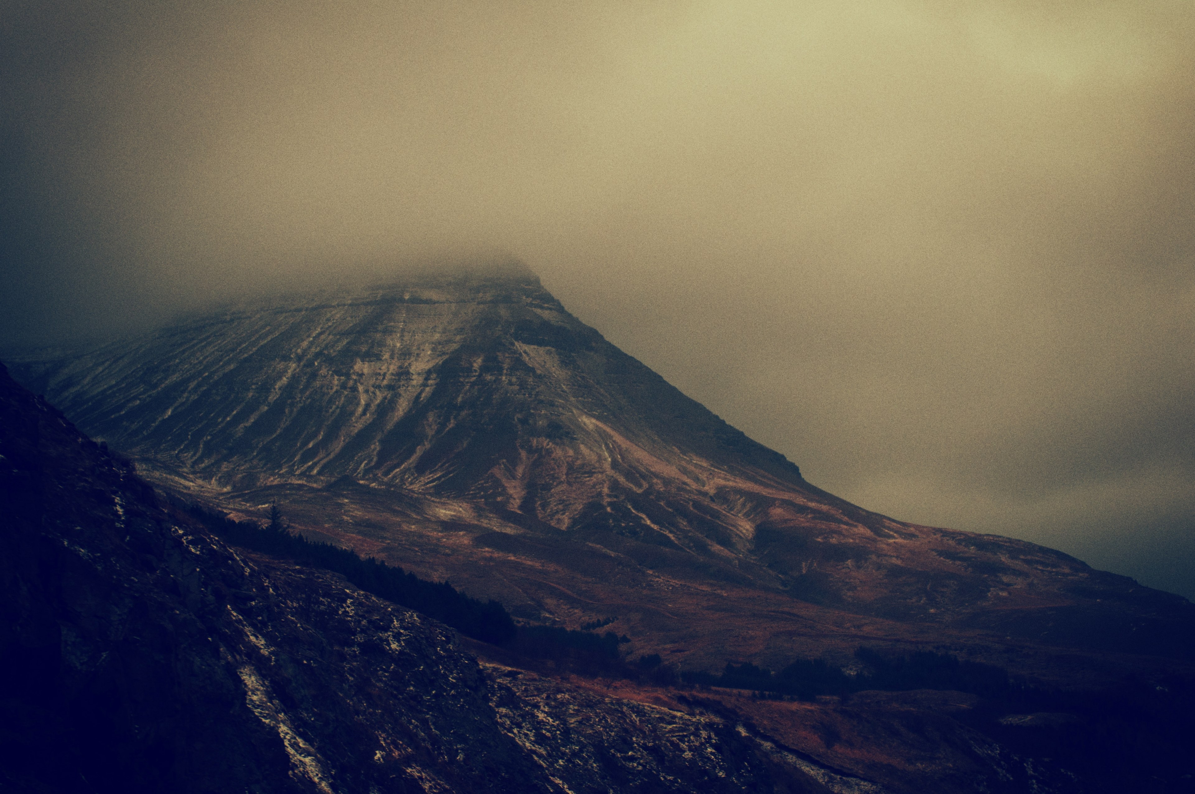 a somber shot of a massive mountain with its peak enveloped by clouds, towering mountain in the clouds 4k, HD Wallpaper