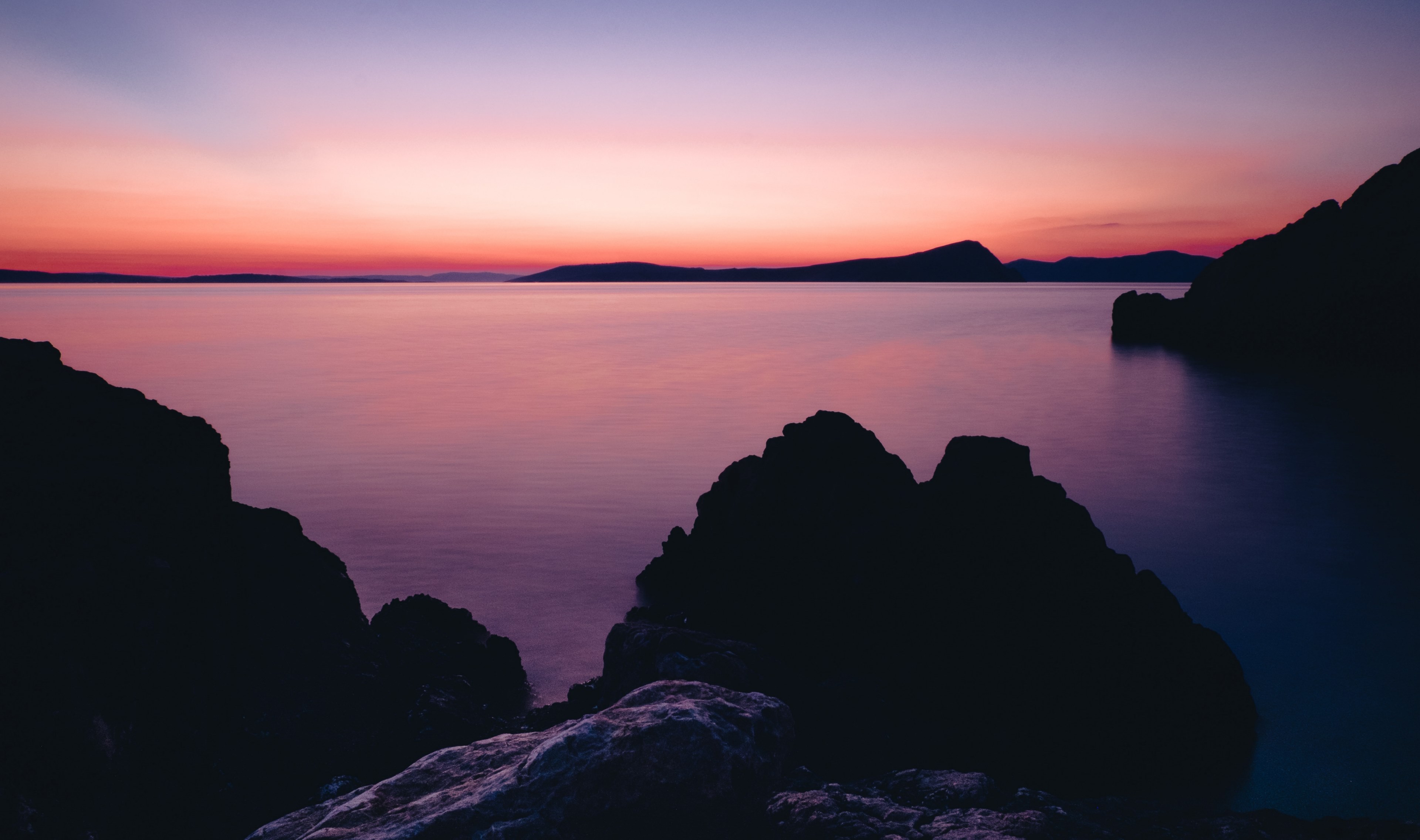placid waters under a pink and purple sky with rocky coasts along the water, rock sunset sea and water 4k, HD Wallpaper
