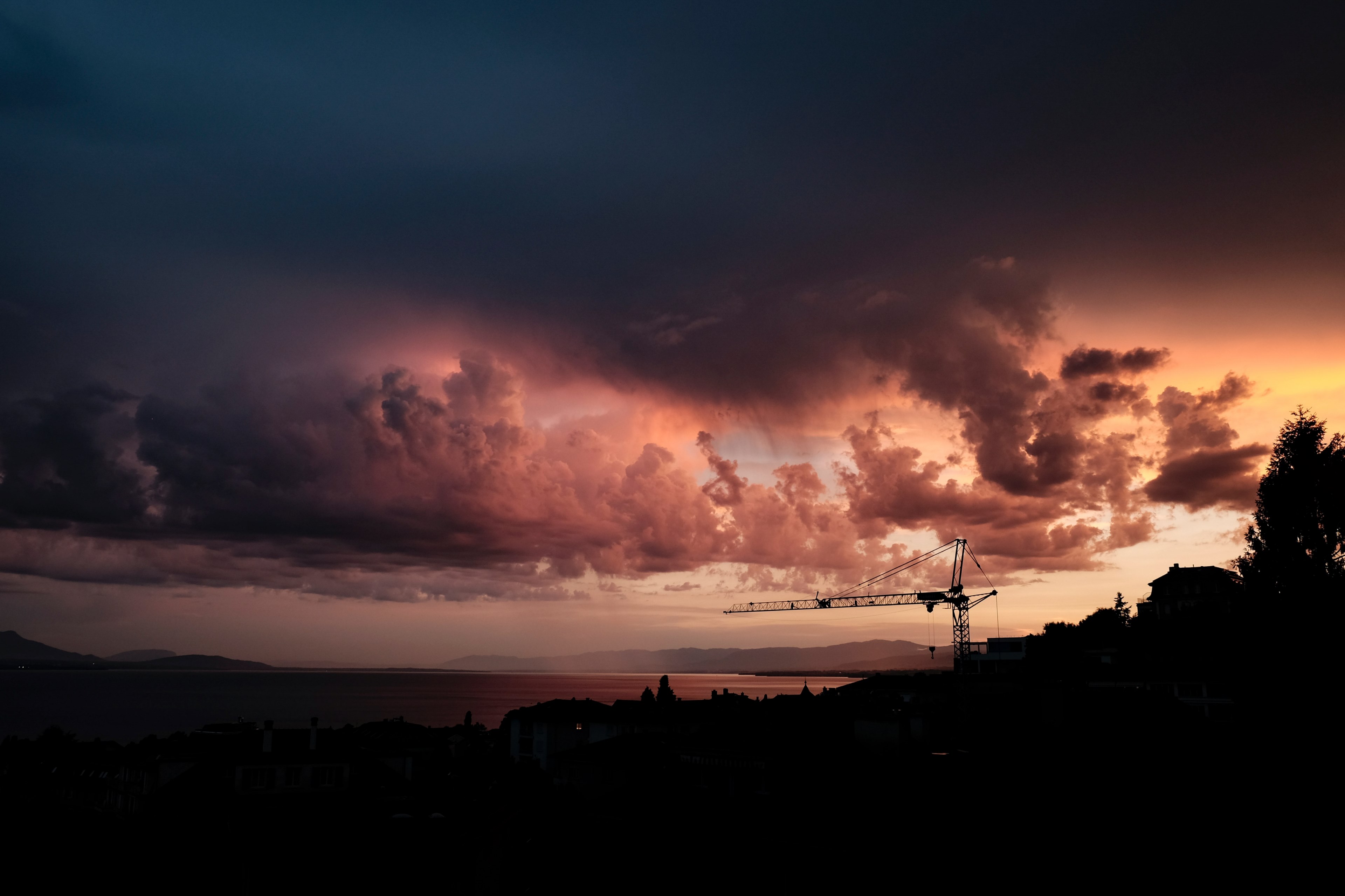 a distant crane and coastal landscape with an overcast cloudy sky at sunset lausanne, crane and clouds 4k, HD Wallpaper