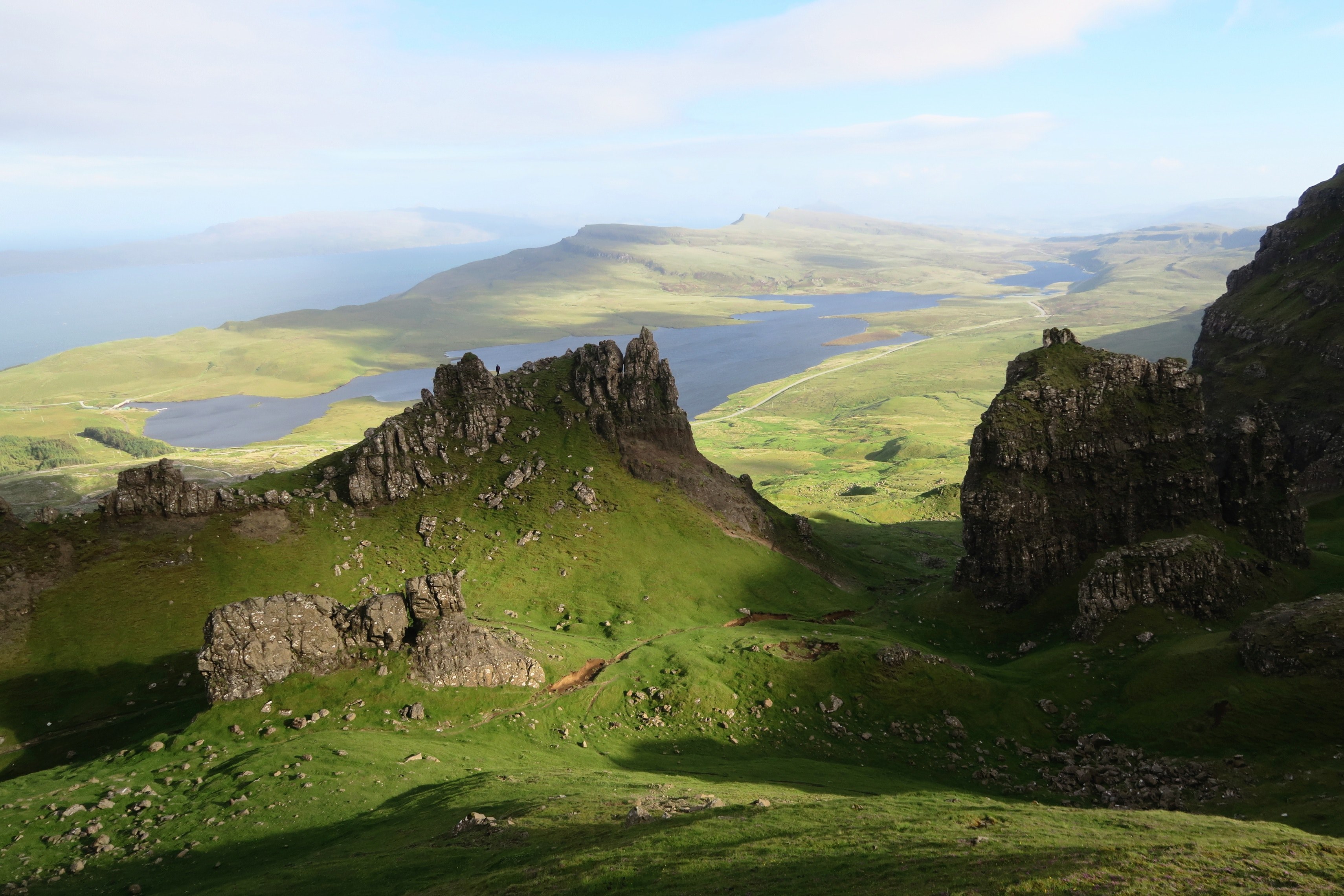 view from the side of a mountain on jagged rock towers and a green valley with a lake in the distance, impressive mountainous landscape 4k, HD Wallpaper
