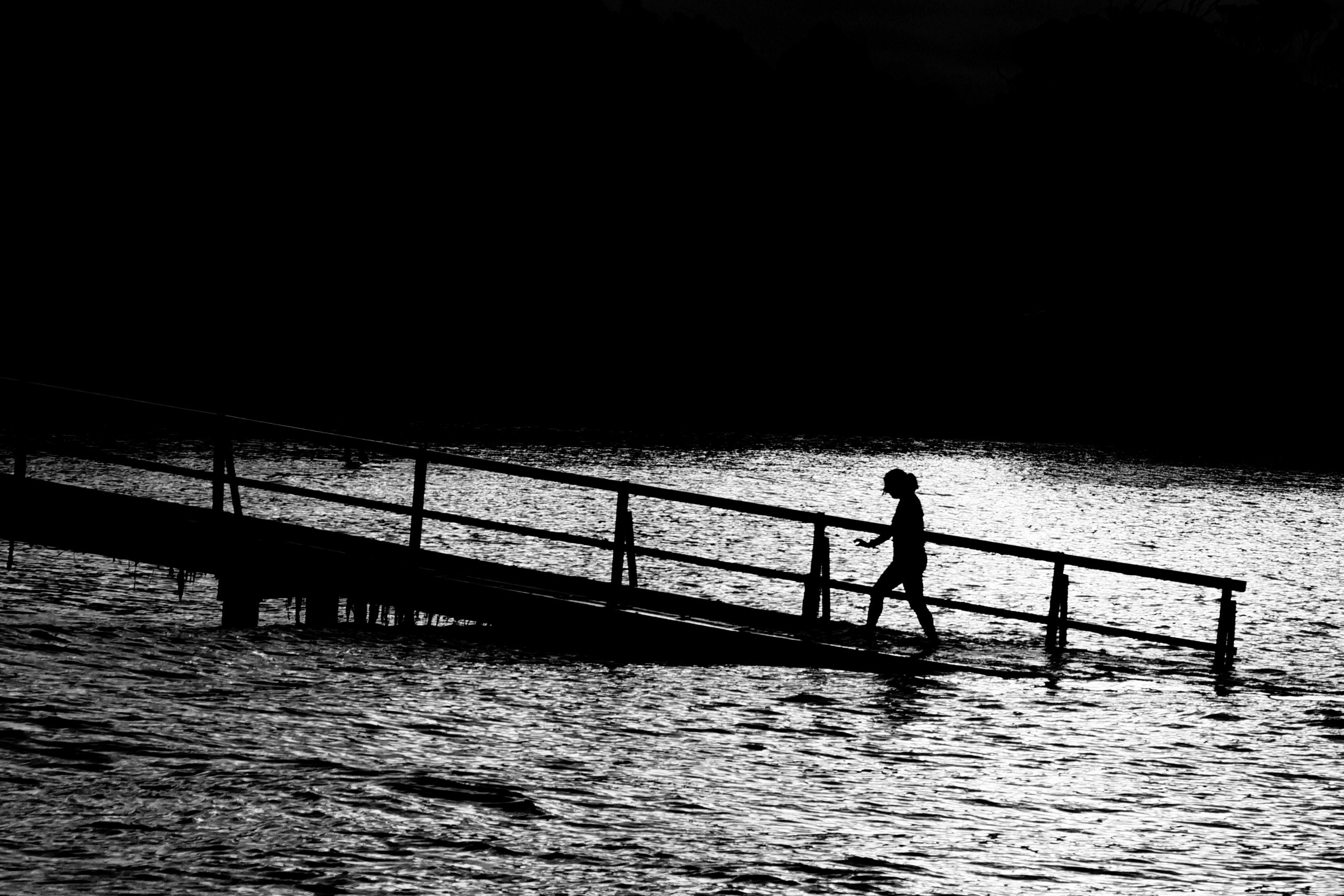 black and white shot of person walking in pier sinking into water, monochrome sinking pier 4k, HD Wallpaper