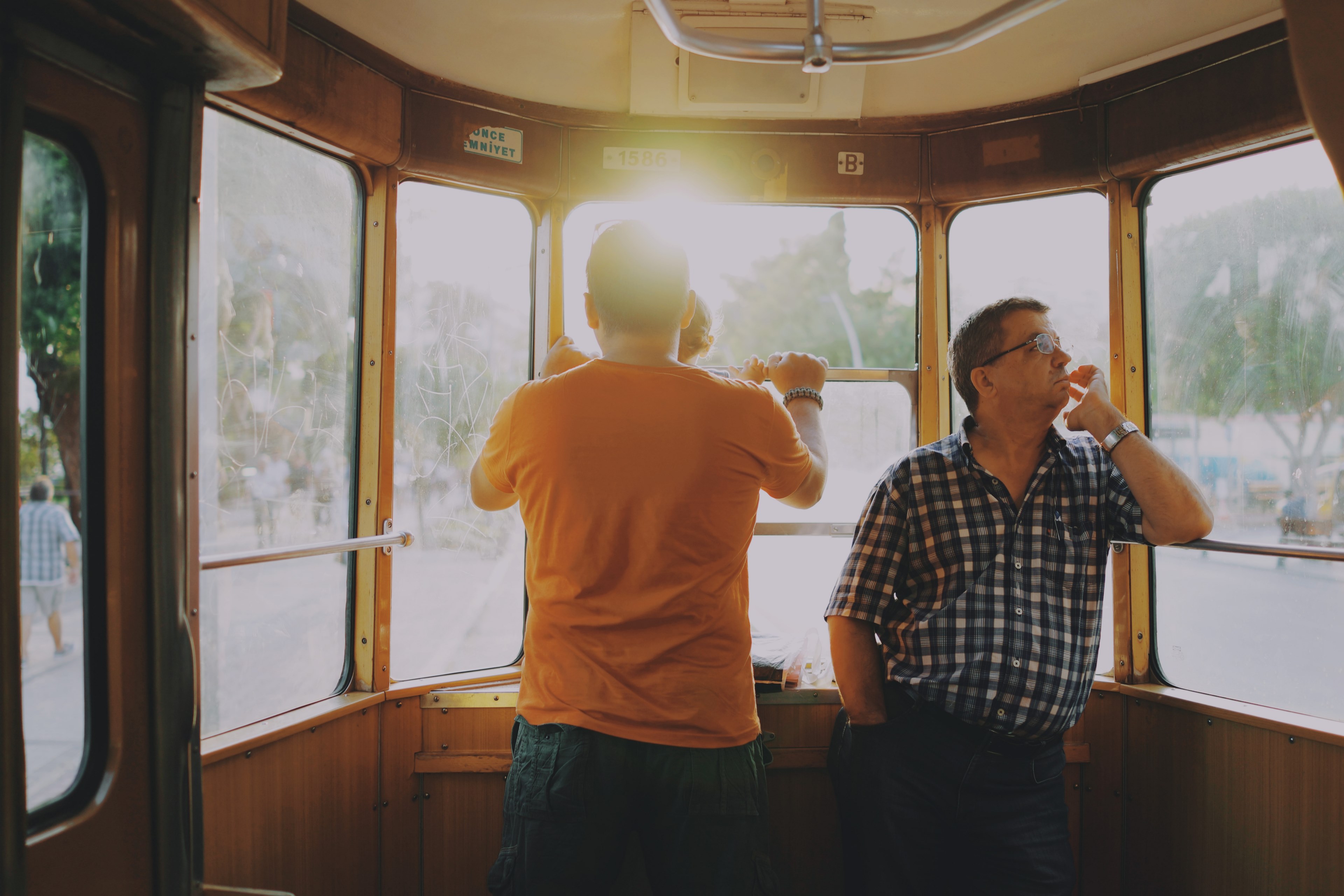 two men wearing watches standing in a streetcar while watching the sun rise over a street, streetcar views with dad 4k, HD Wallpaper