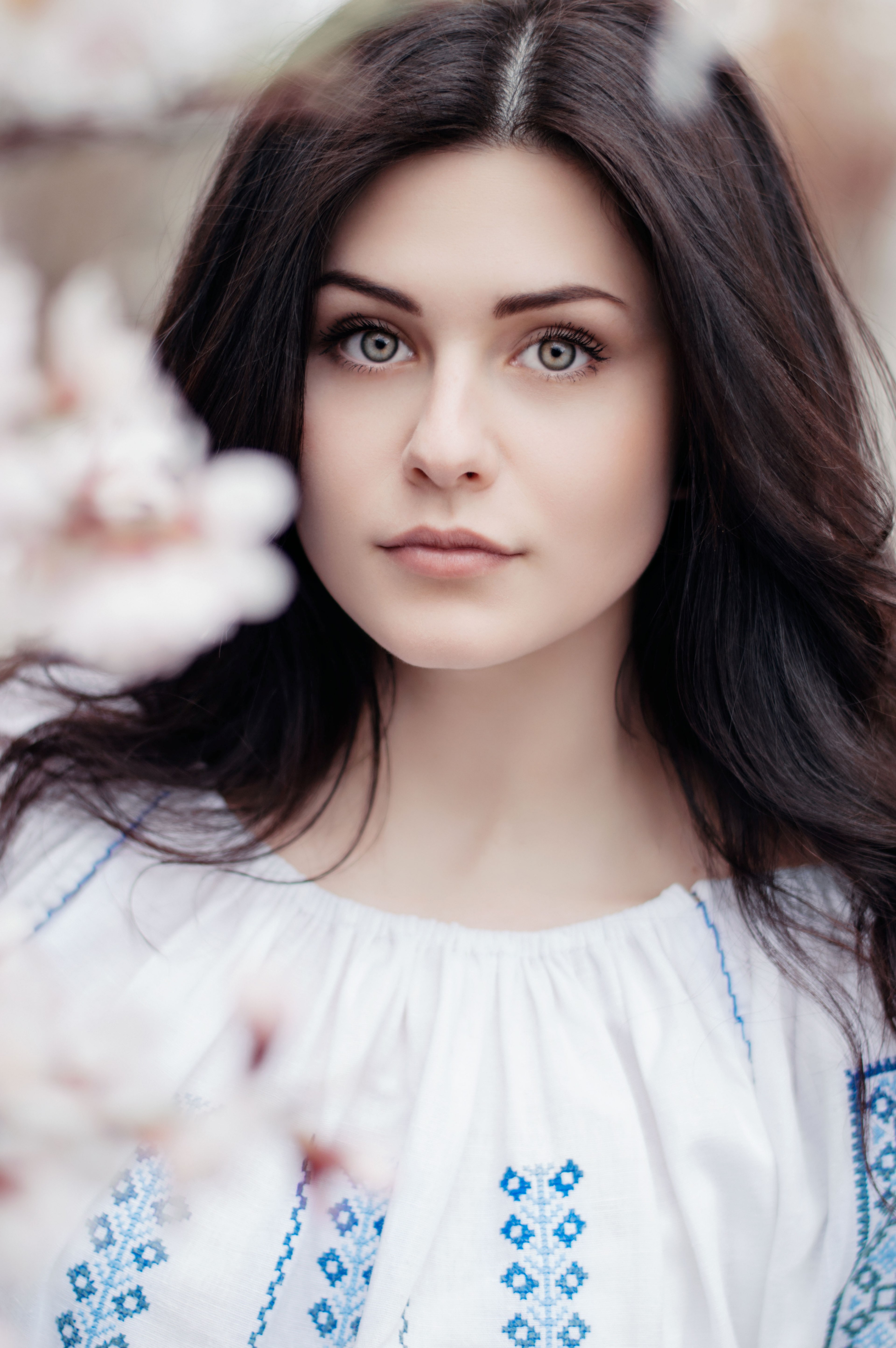 a woman with long brown hair stands behind blurred cherry blossom branches in chisinau, woman behind cherry blossoms 4k, Phone HD Wallpaper