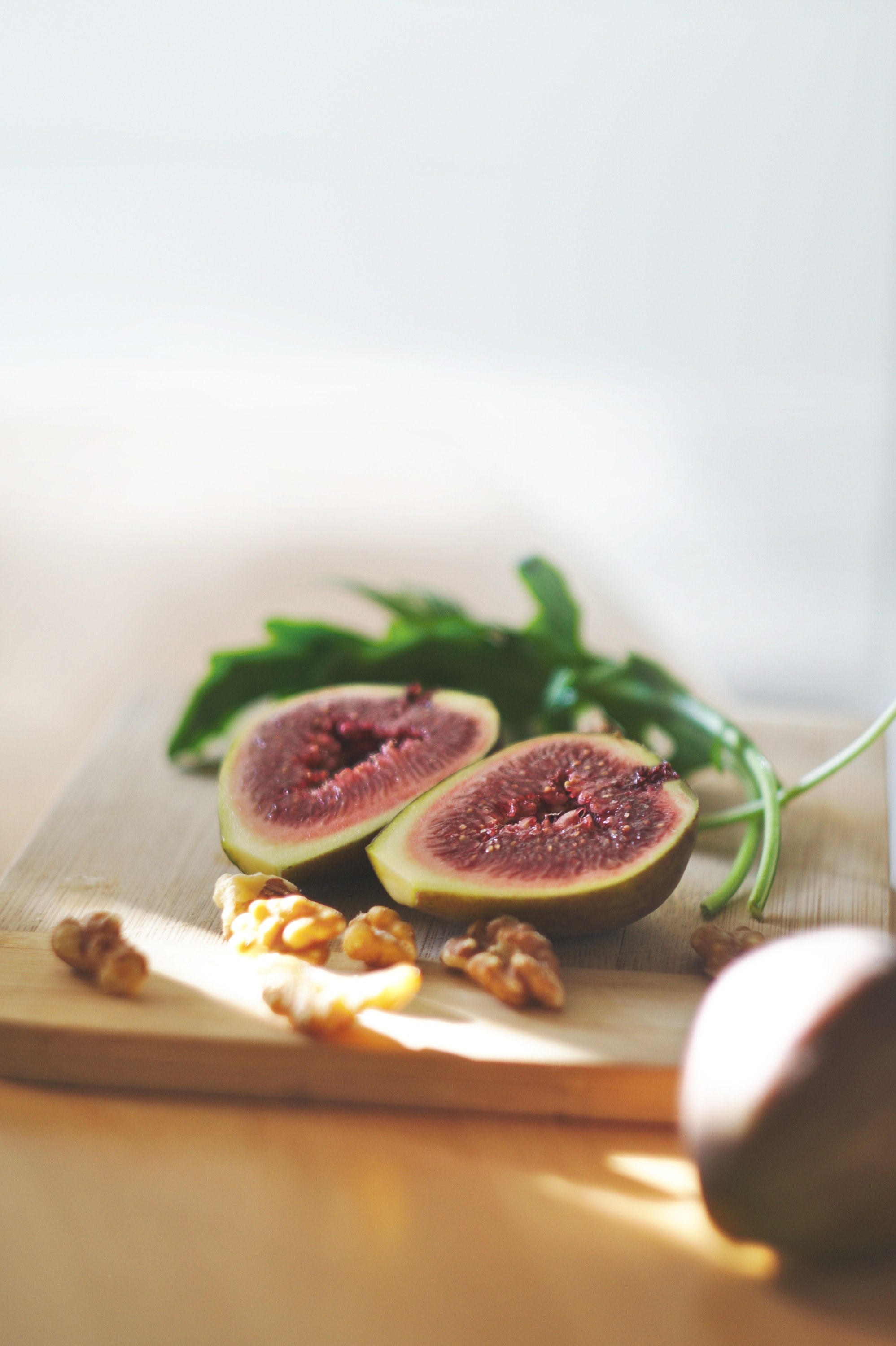 cutting board with a fig fruit cut in half a sprig of arugula and walnuts, inside a fig 4k, Phone HD Wallpaper
