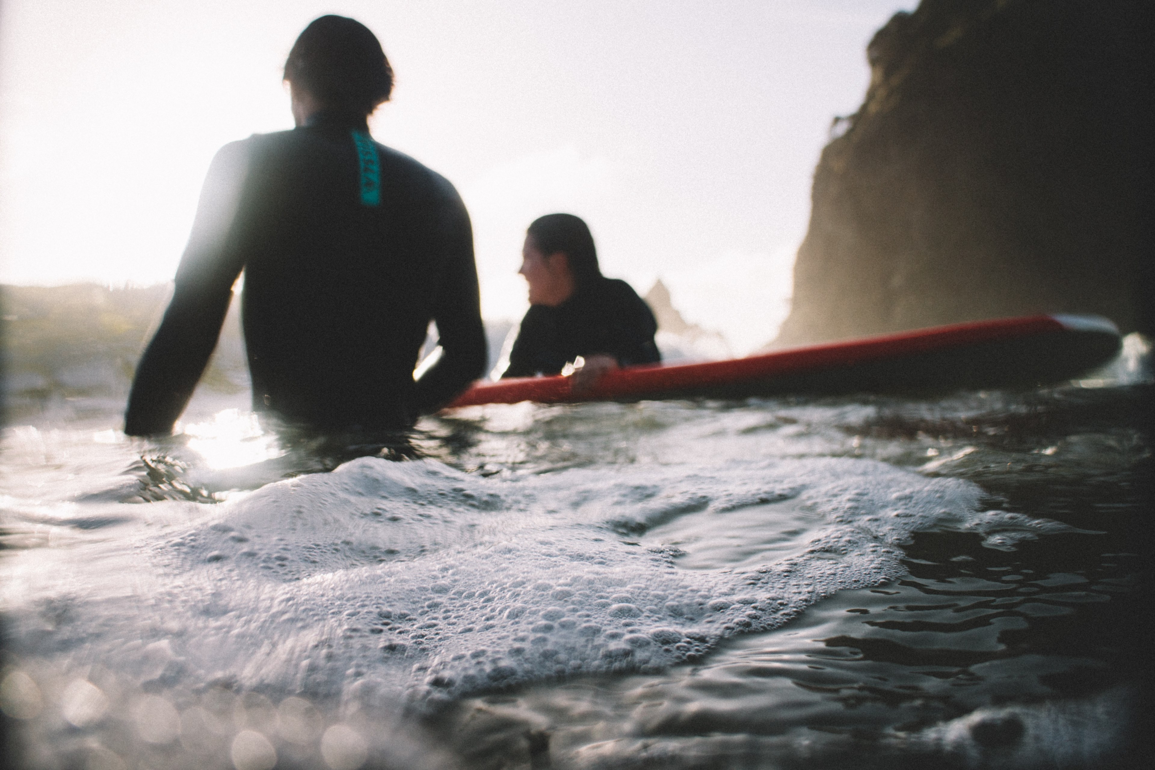 two surfers in wetsuits with a surfboard in the foamy ocean at piha beach, relaxing surfers at piha beach 4k, HD Wallpaper