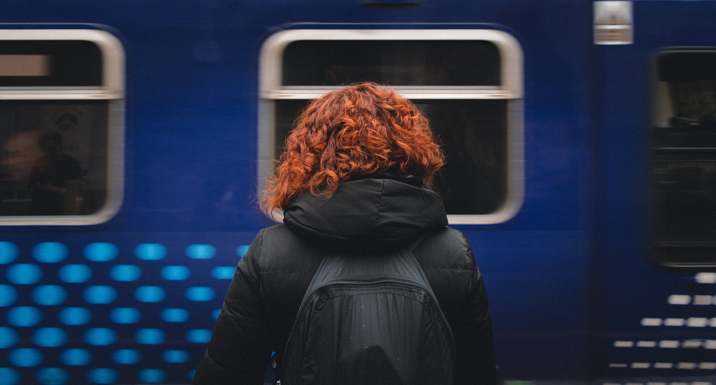 a person with curly red hair faces away toward a moving blue train in mount florida, person facing train 4k, HD Wallpaper