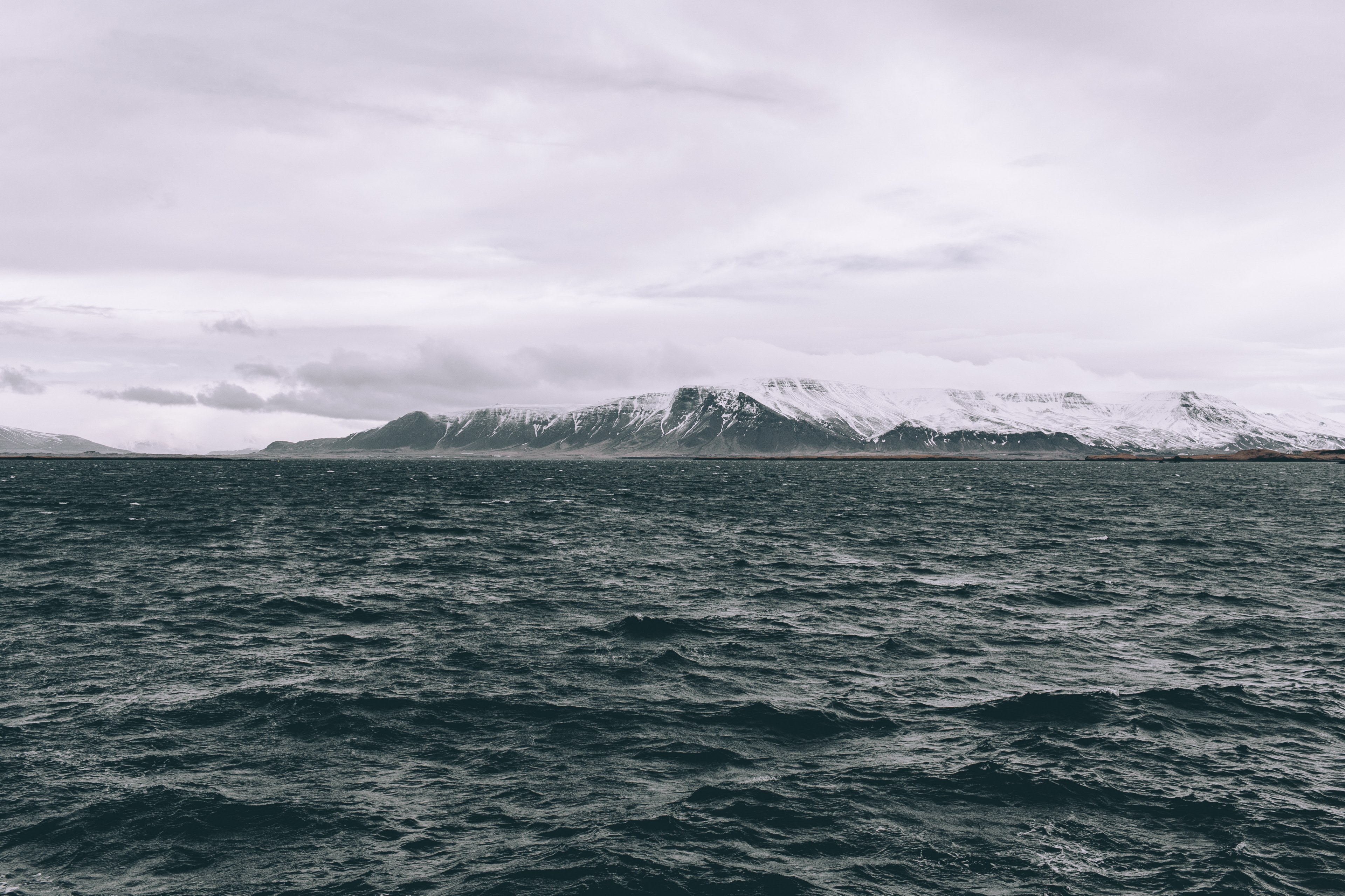 ocean around cloudy iceland with snow capped rocks and mountains at the horizon, rough waters in reykjavik 4k, HD Wallpaper