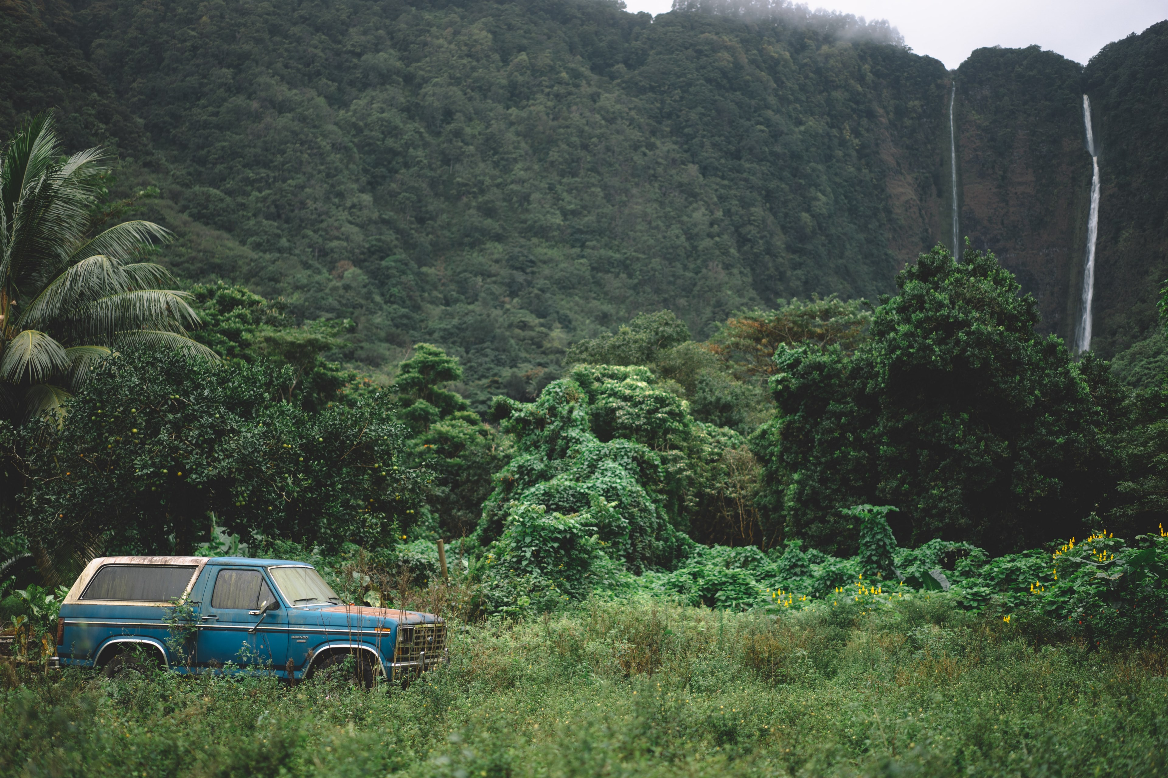 a blue suv parked in the green thicket near rock face with twin waterfalls, off road trip to the waterfall 4k, HD Wallpaper