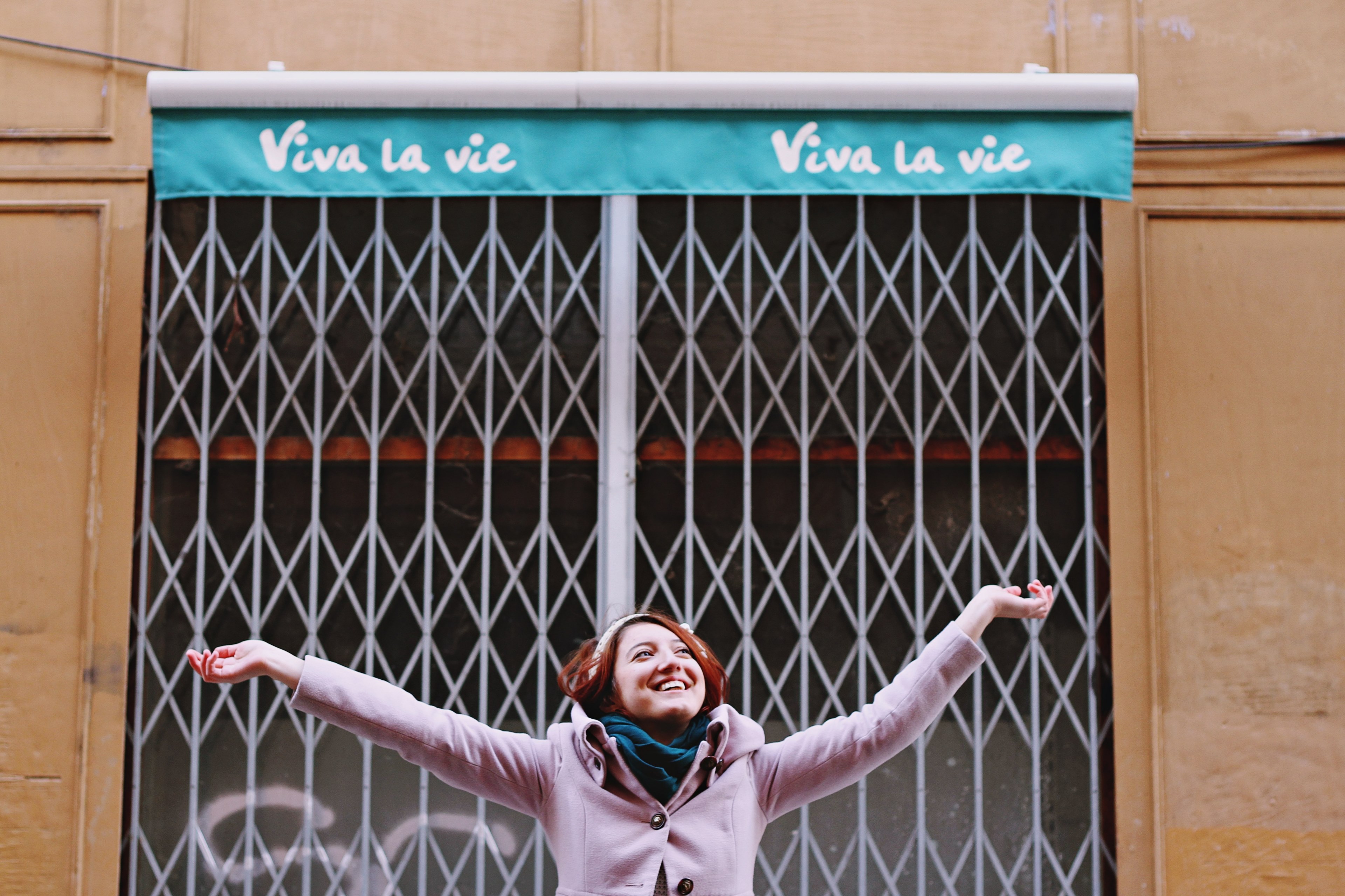a woman smiling with outstretched arms in front of a closed storefront in toulouse, woman with outstretched arms 4k, HD Wallpaper