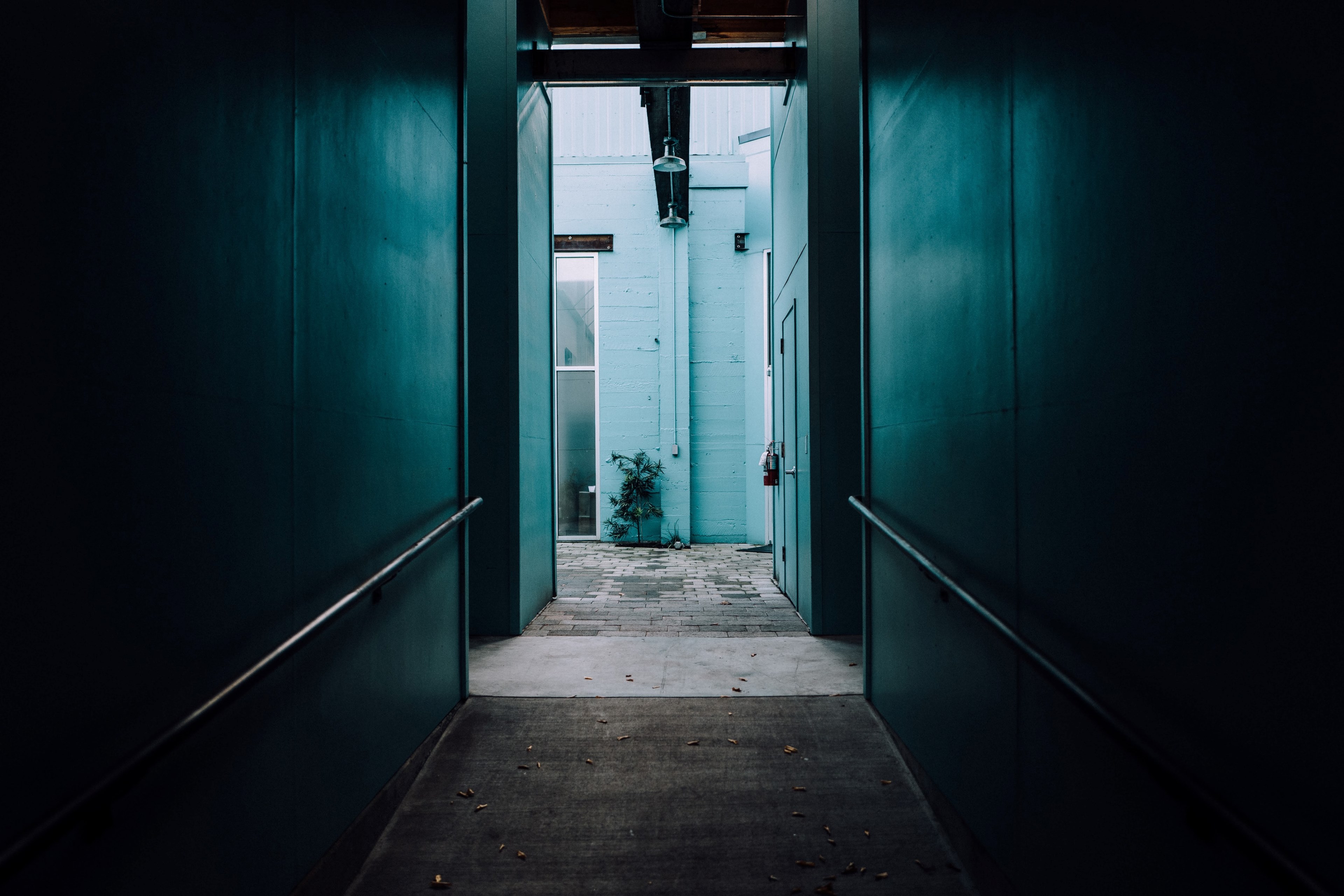 the corridor of a dark blue wall with hand railings on it in sonsie style, looking from dark to light 4k, HD Wallpaper