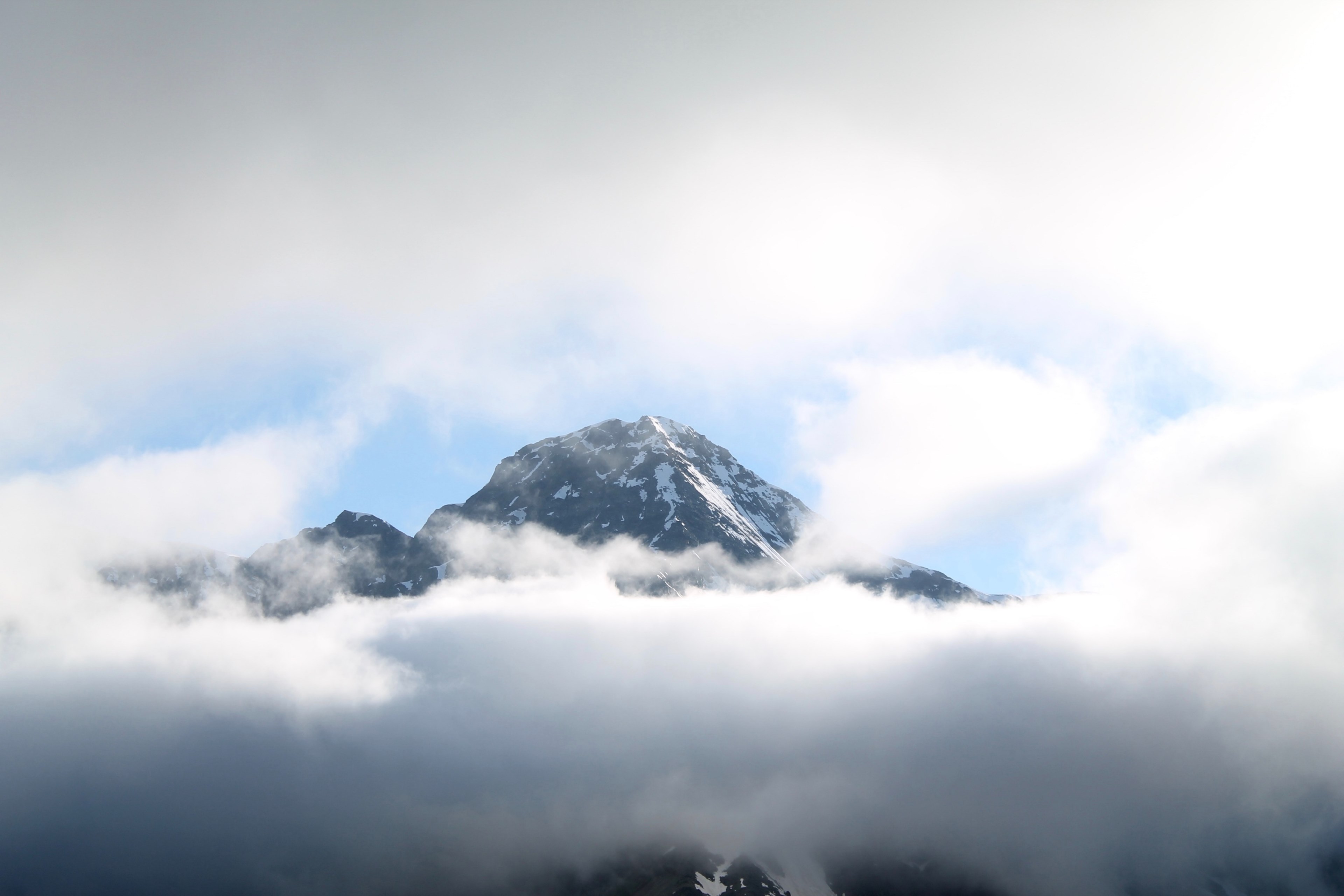 thick clouds envelop a tall mountain peak partly obscuring the view, mountain behind thick clouds 4k, HD Wallpaper