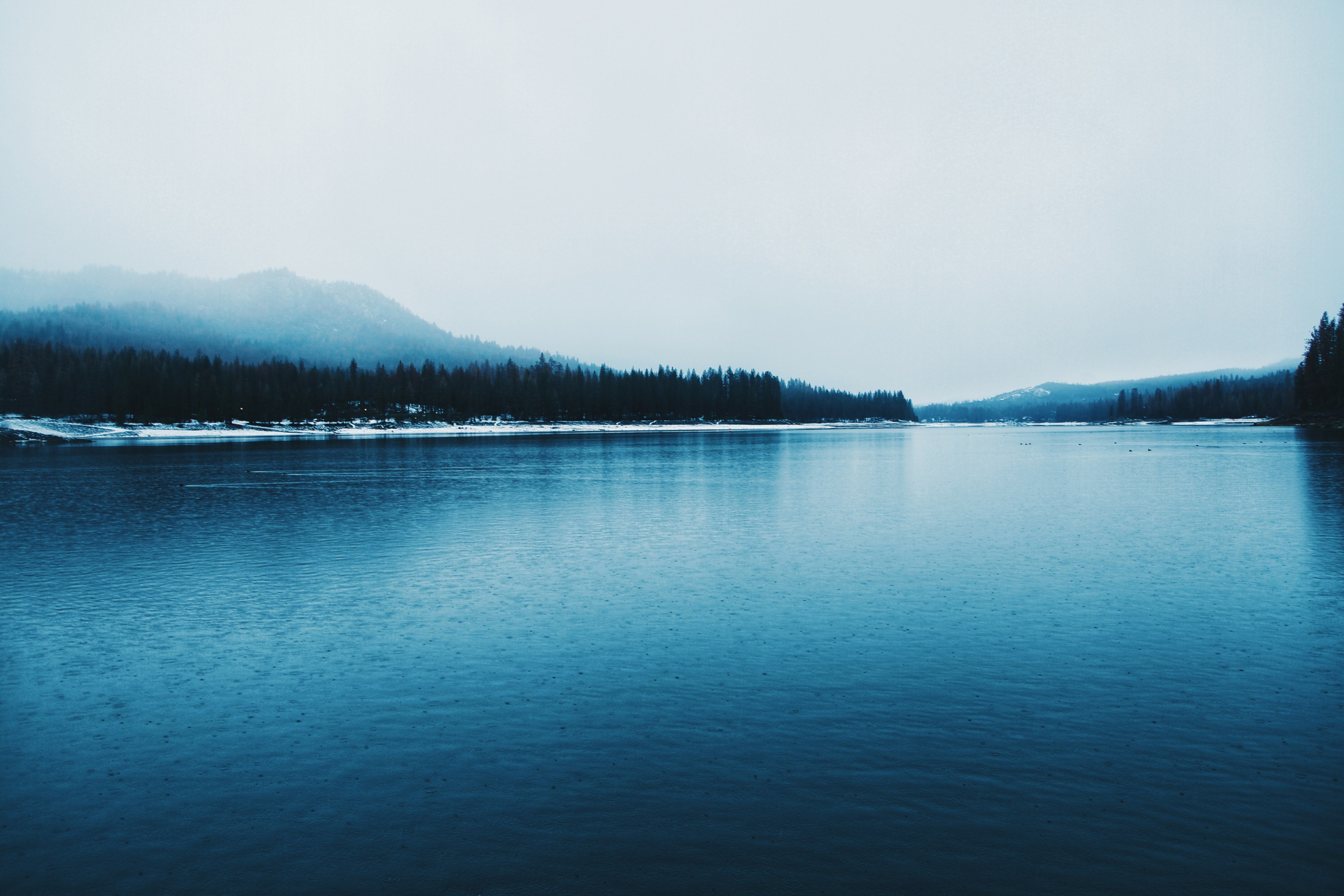 the surface of a lake in winter with a wooded hill on the foggy horizon, blue lake in the winter 4k, HD Wallpaper