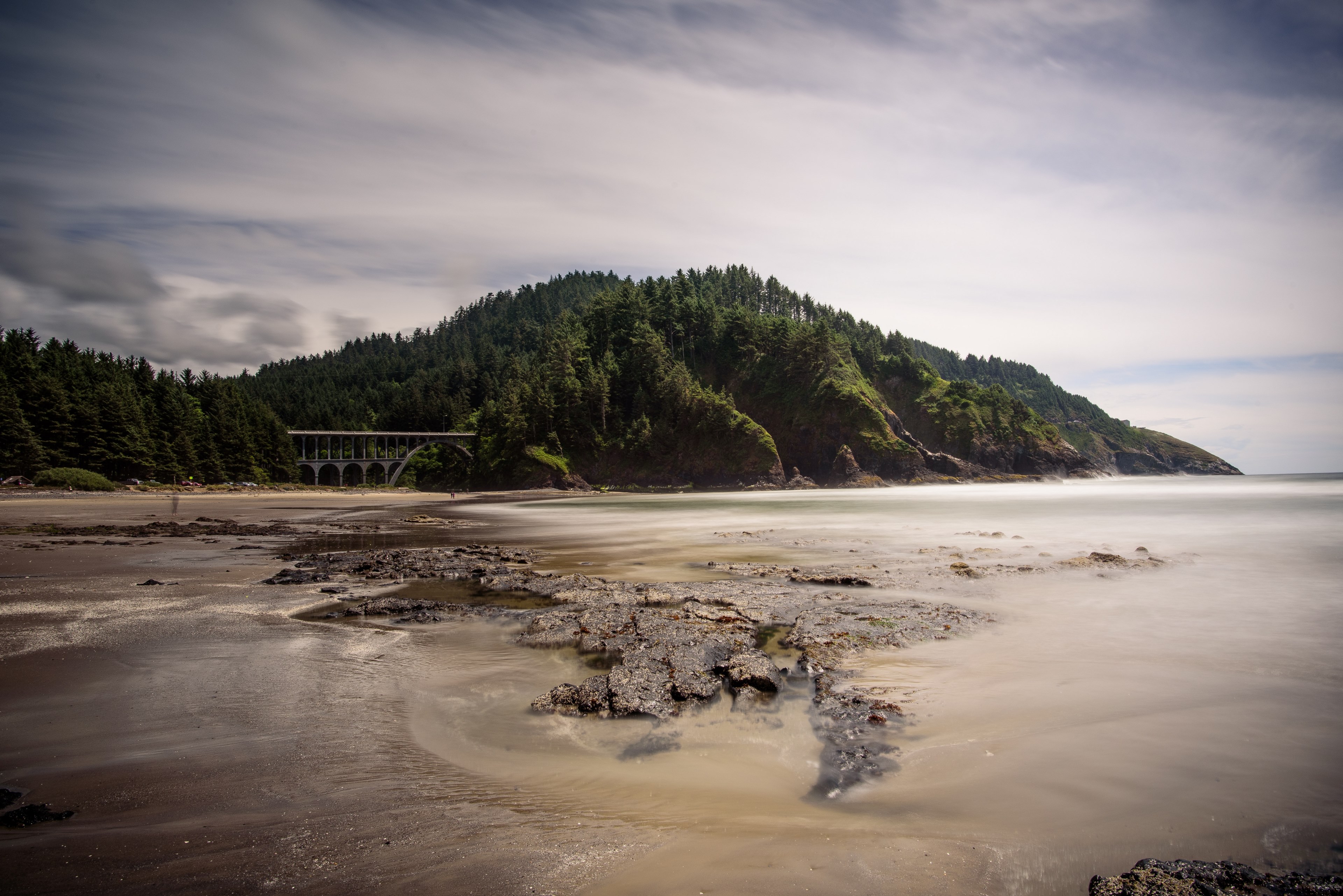 rocks and smooth sea water at the edge of a beach with an aqueduct in the background, aqueduct near a beach 4k, HD Wallpaper