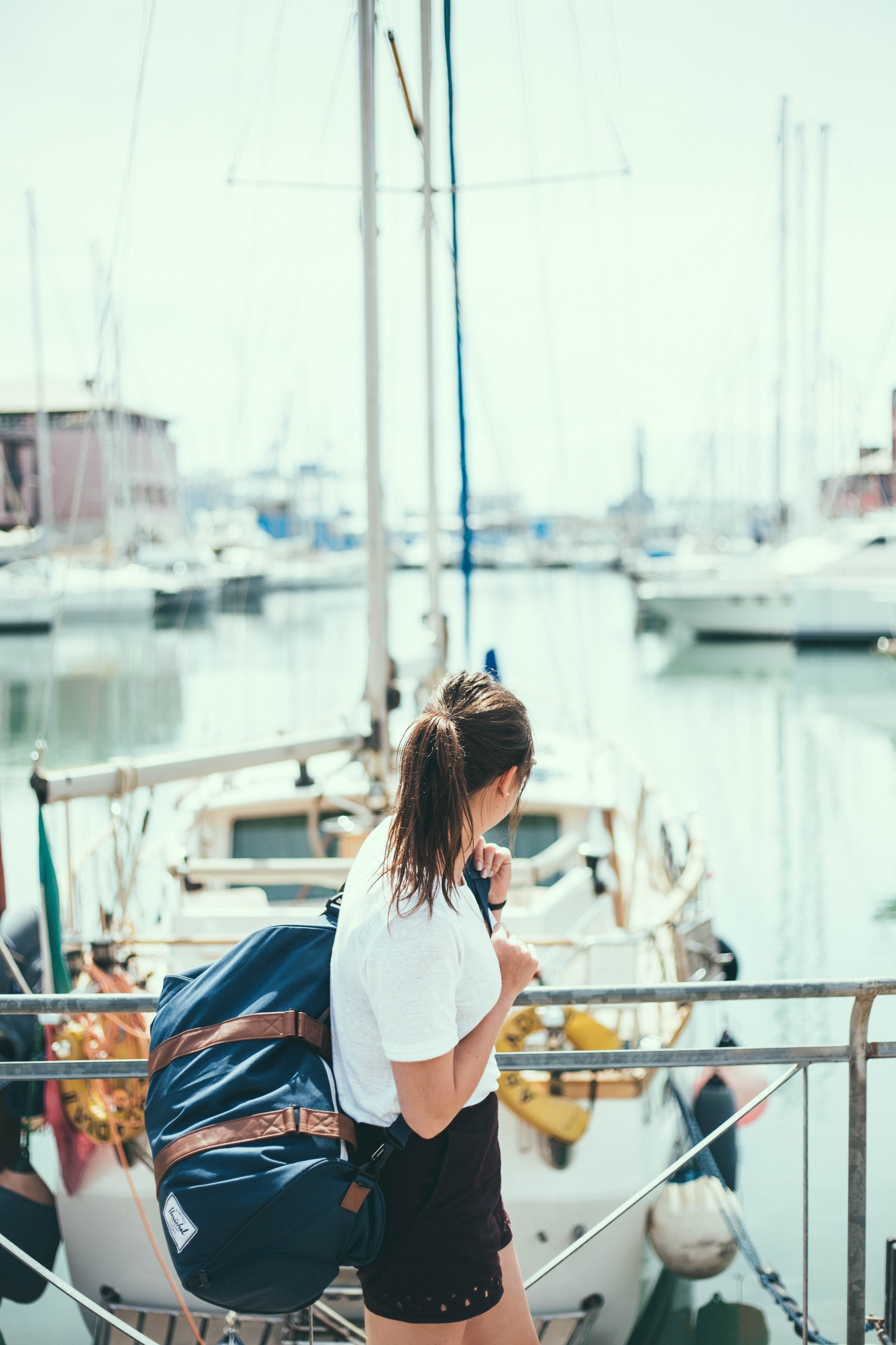 a woman carrying a suitcase looks toward boats at a harbor in genoa, woman in genoa harbor 4k, Phone HD Wallpaper