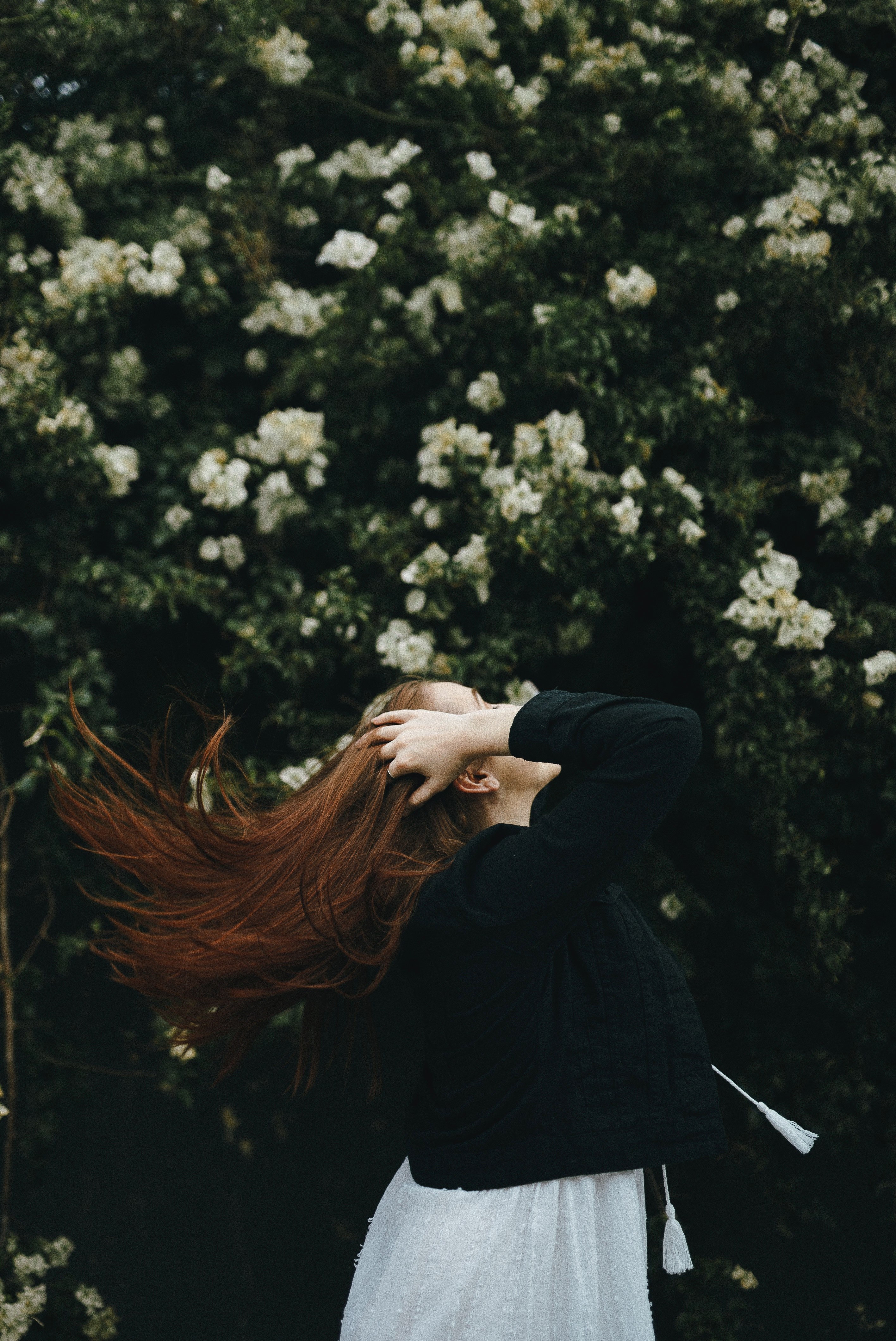 a woman runs her fingers through her long brown hair in front of flowering trees, the white amp red flower 4k, Phone HD Wallpaper