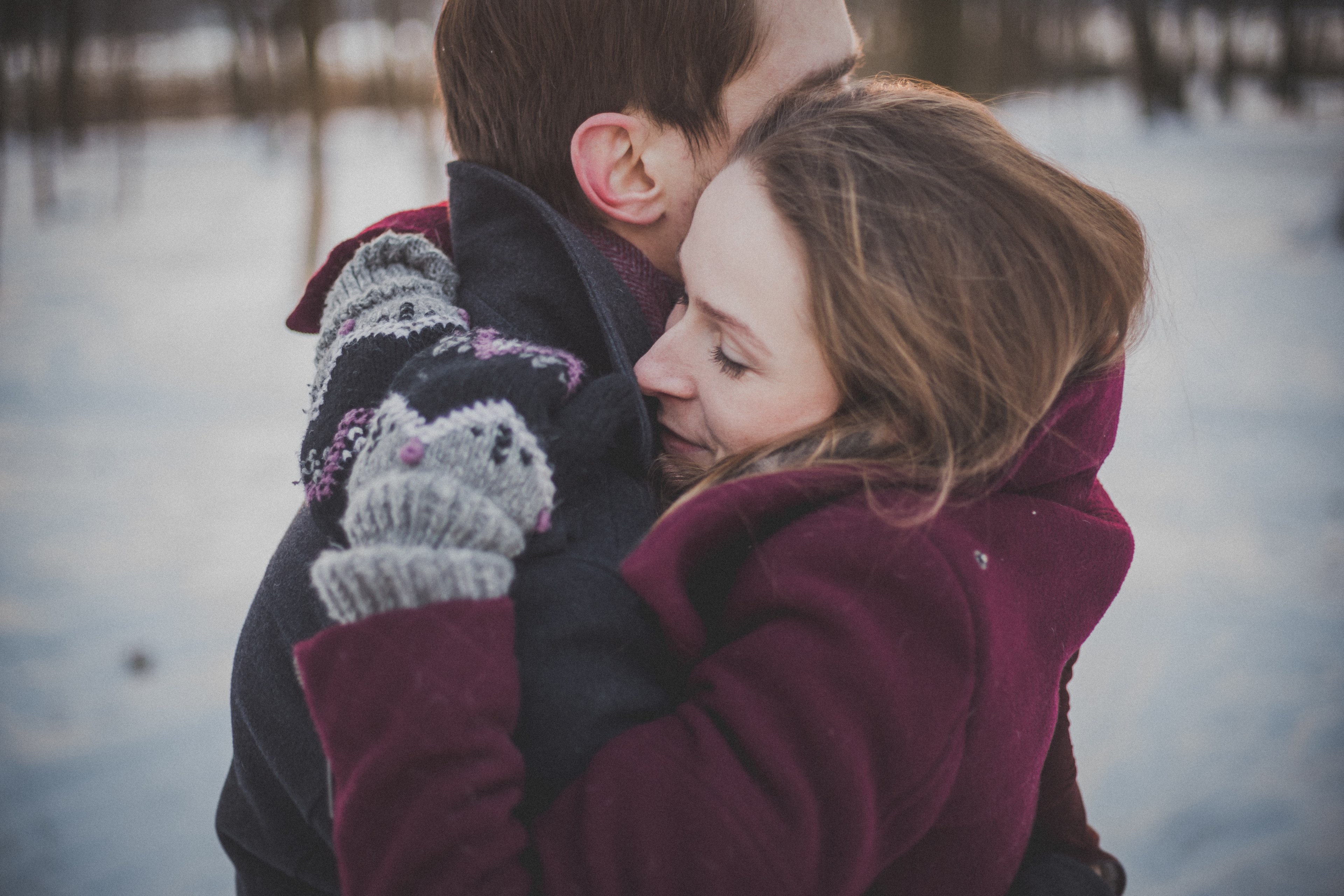 couple in winter clothes hugs outdoors with snow on the ground and trees in the background, hugging in the winter 4k, HD Wallpaper