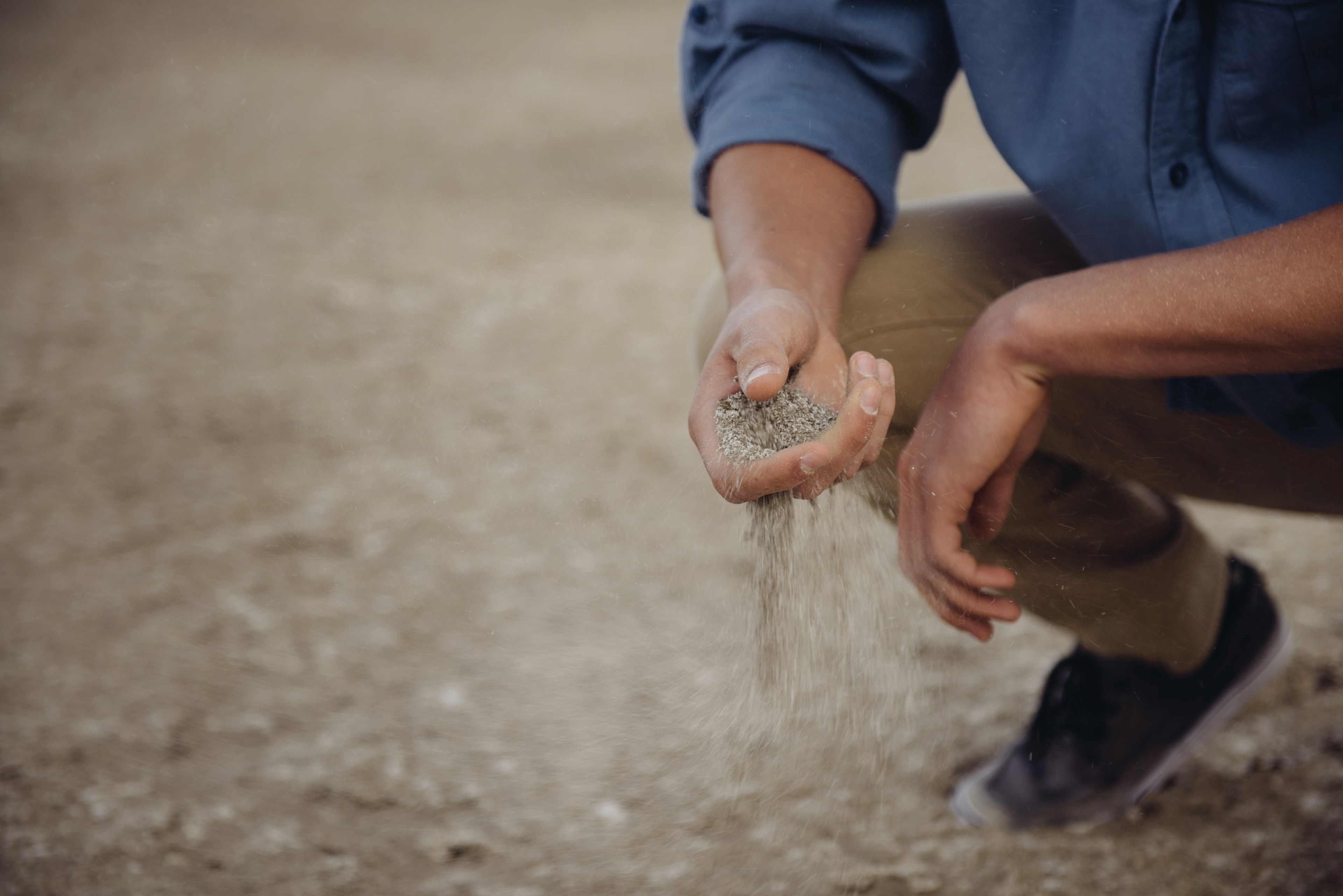 person crouches down with a handful of sand that slips through their fingers, handful of earth 4k, HD Wallpaper