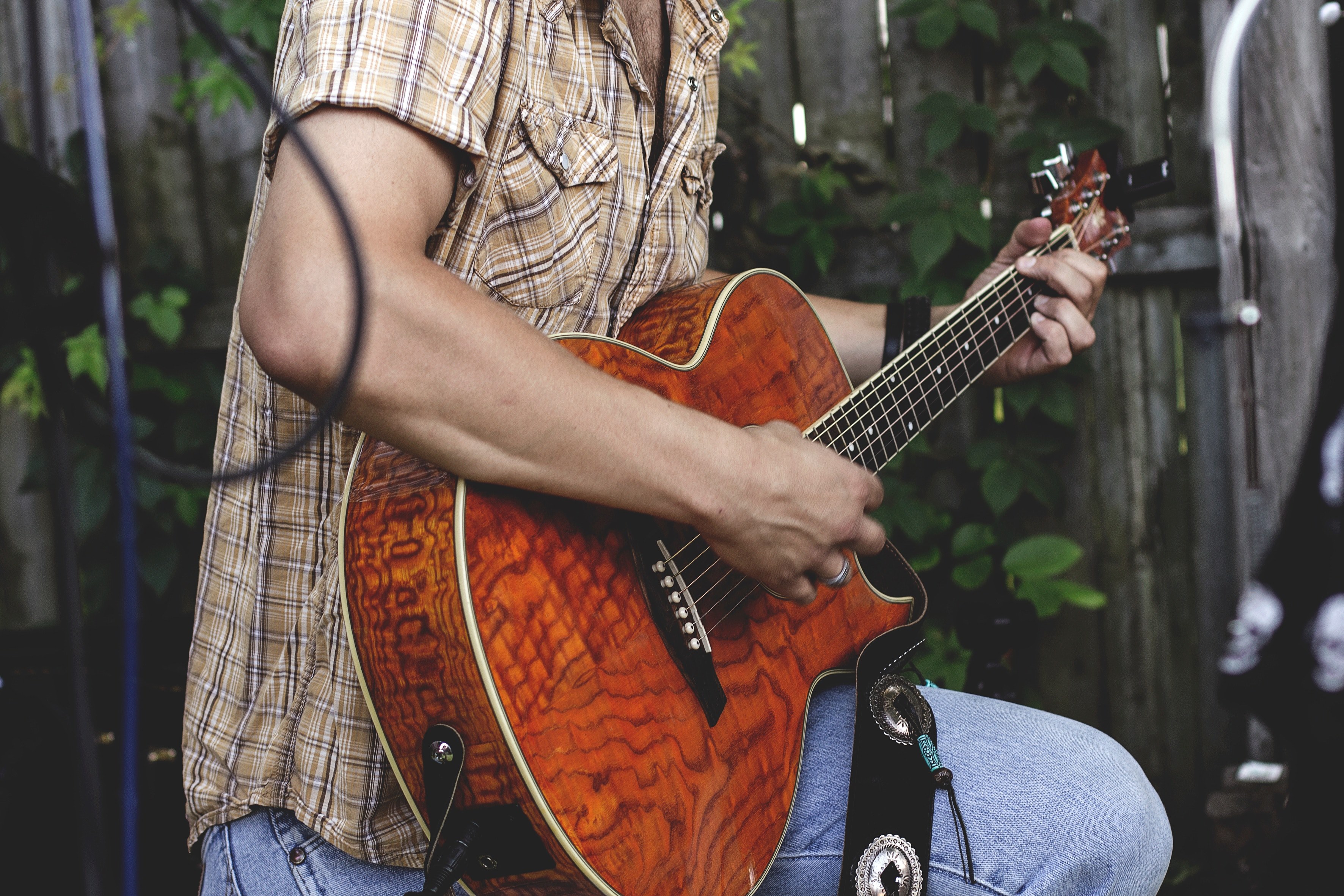 a man in a checkered shirt strumming an acoustic guitar in a garden, guitar player in a garden 4k, HD Wallpaper