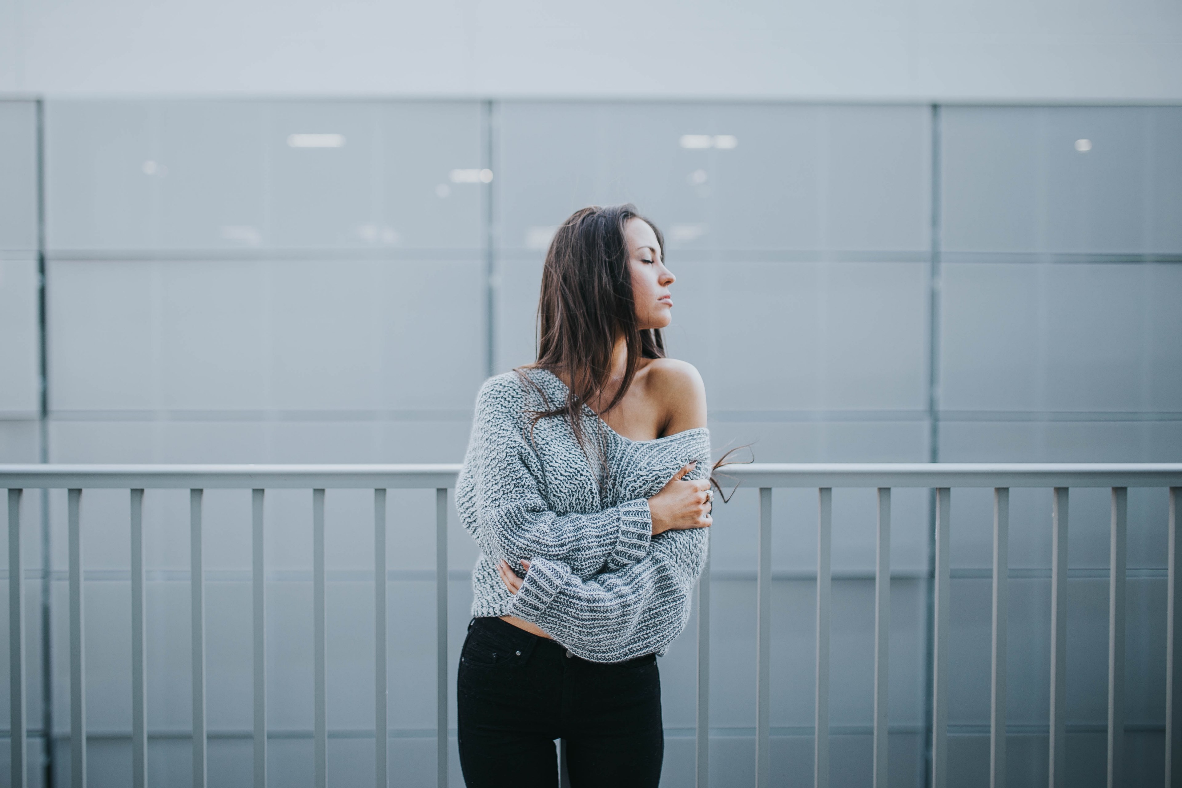 a woman in an off the shoulder sweater stands in front of a white railing and white wall, woman by white railing 4k, HD Wallpaper