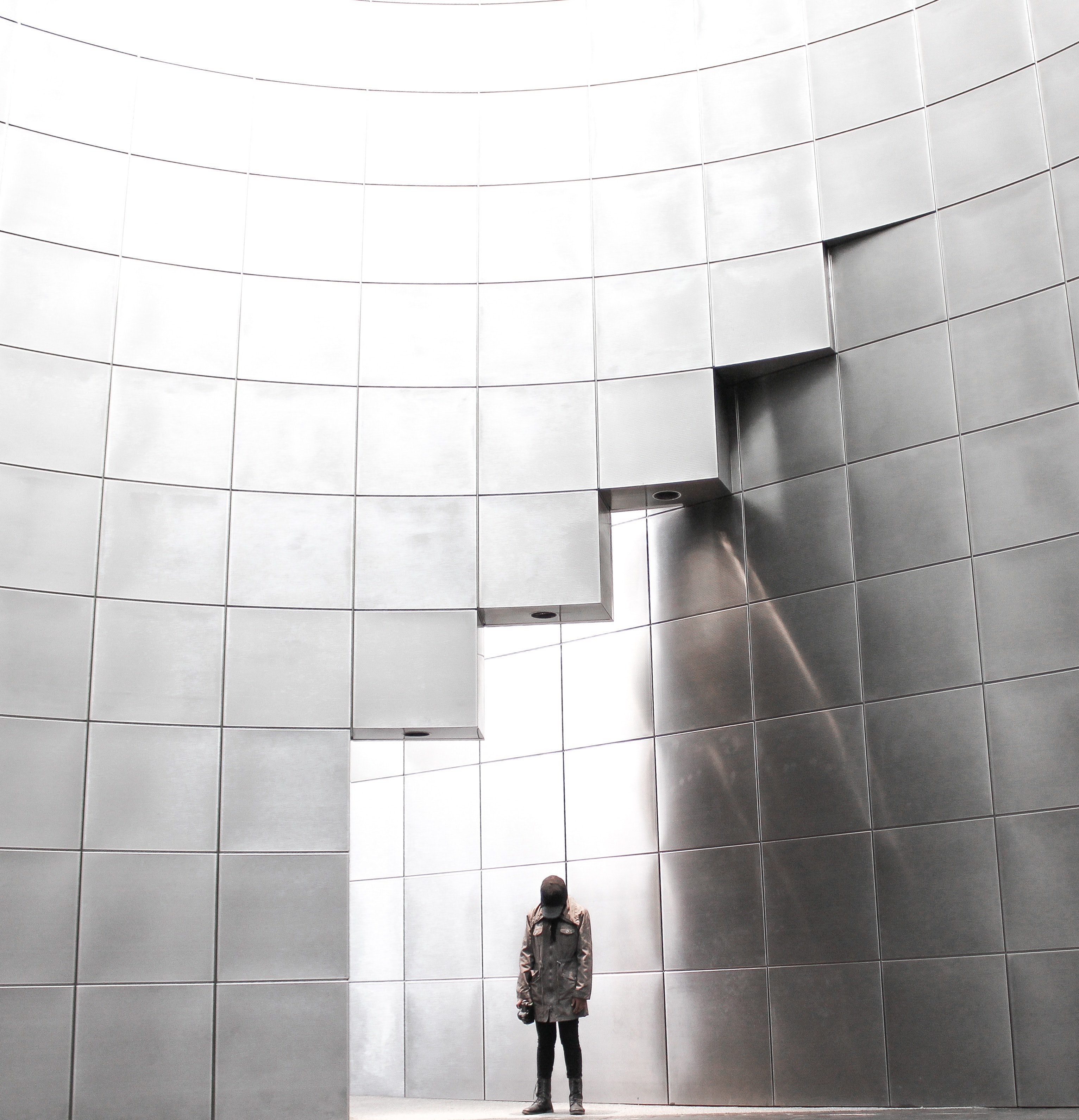 person in a coat stands near a shiny silver wall in a grid pattern, all the way up 4k, Phone HD Wallpaper