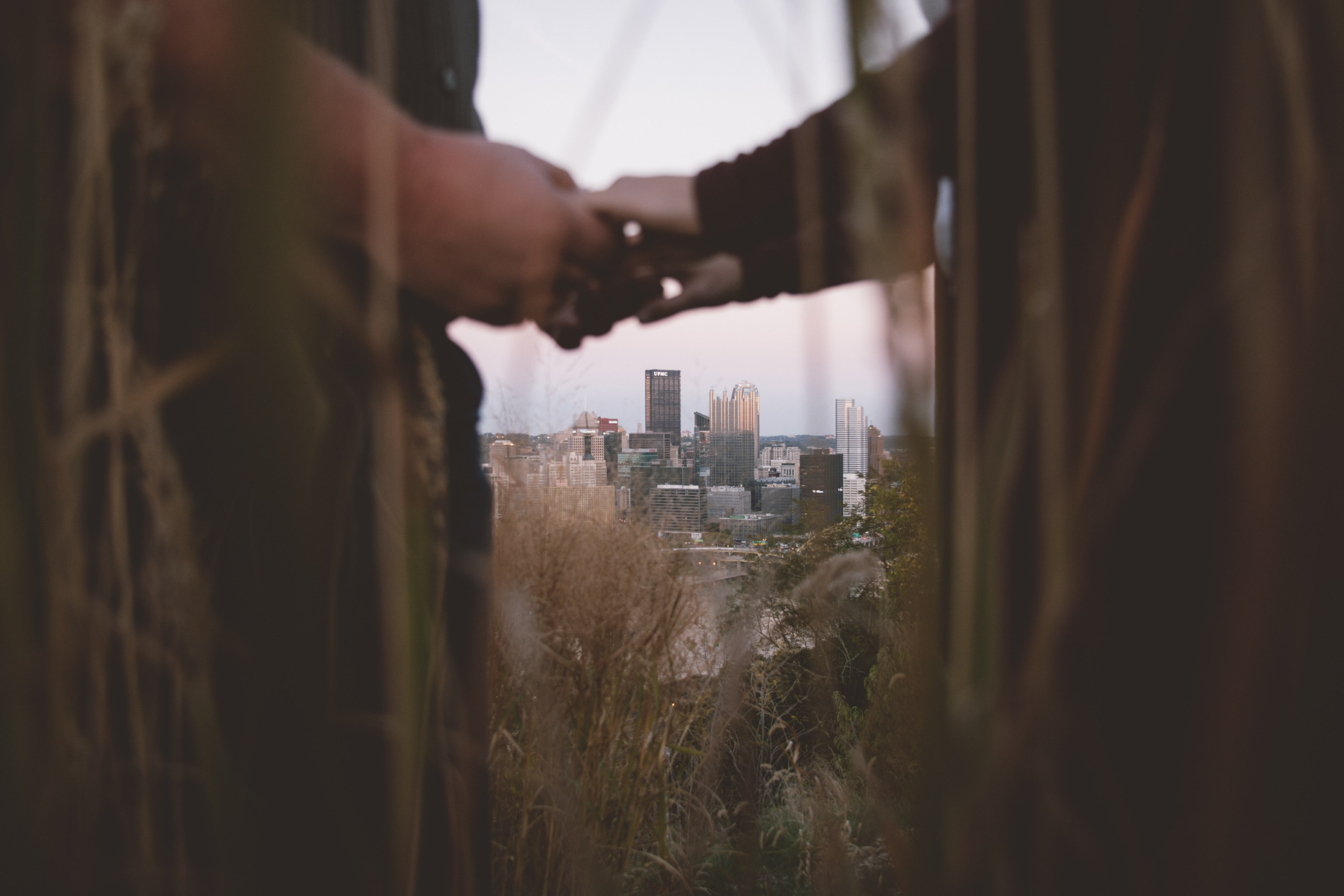 a couple is seen holding hands through tall grasses with the pittsburgh skyline in the background, holding hands in pittsburgh 4k, HD Wallpaper