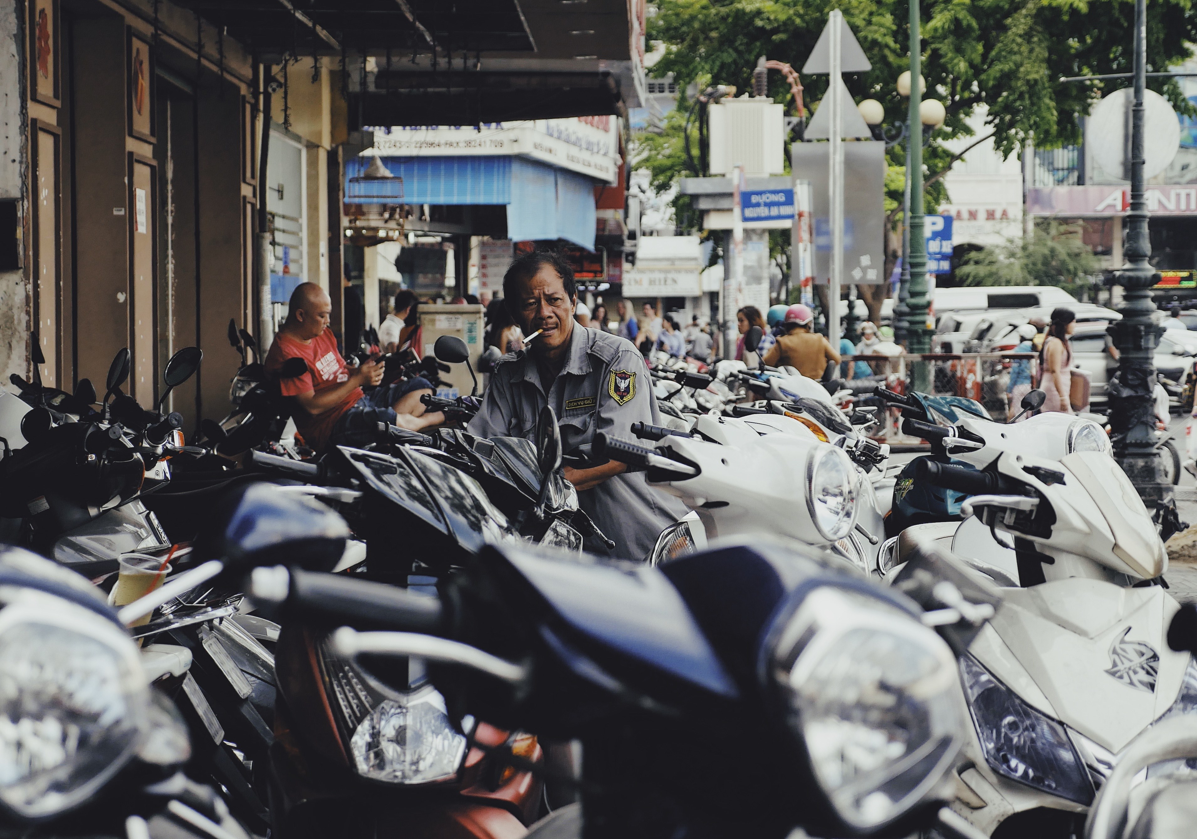 a man smokes a cigarette while standing among an array of motor scooters in the city, man smoking with scooters 4k, HD Wallpaper