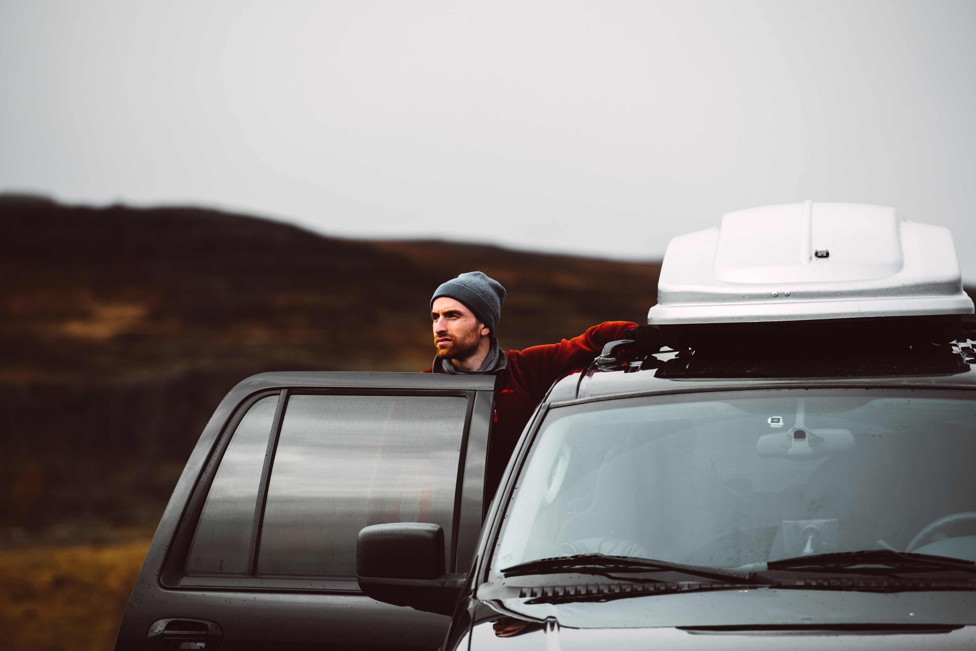 a bearded man in a beanie stepping outside his car in the icelandic wilderness, road trip in iceland 4k, HD Wallpaper
