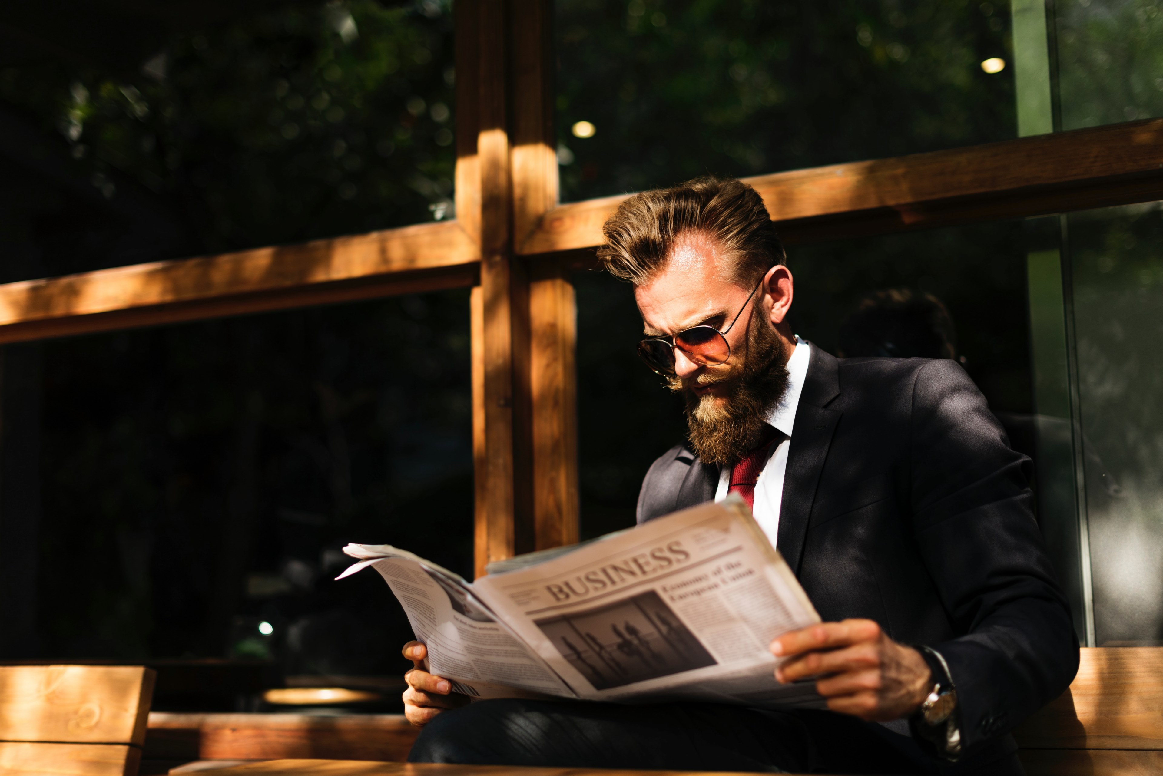 an elegant bearded man in a suit reading a newspaper on a wooden bench, businessman with a paper 4k, HD Wallpaper