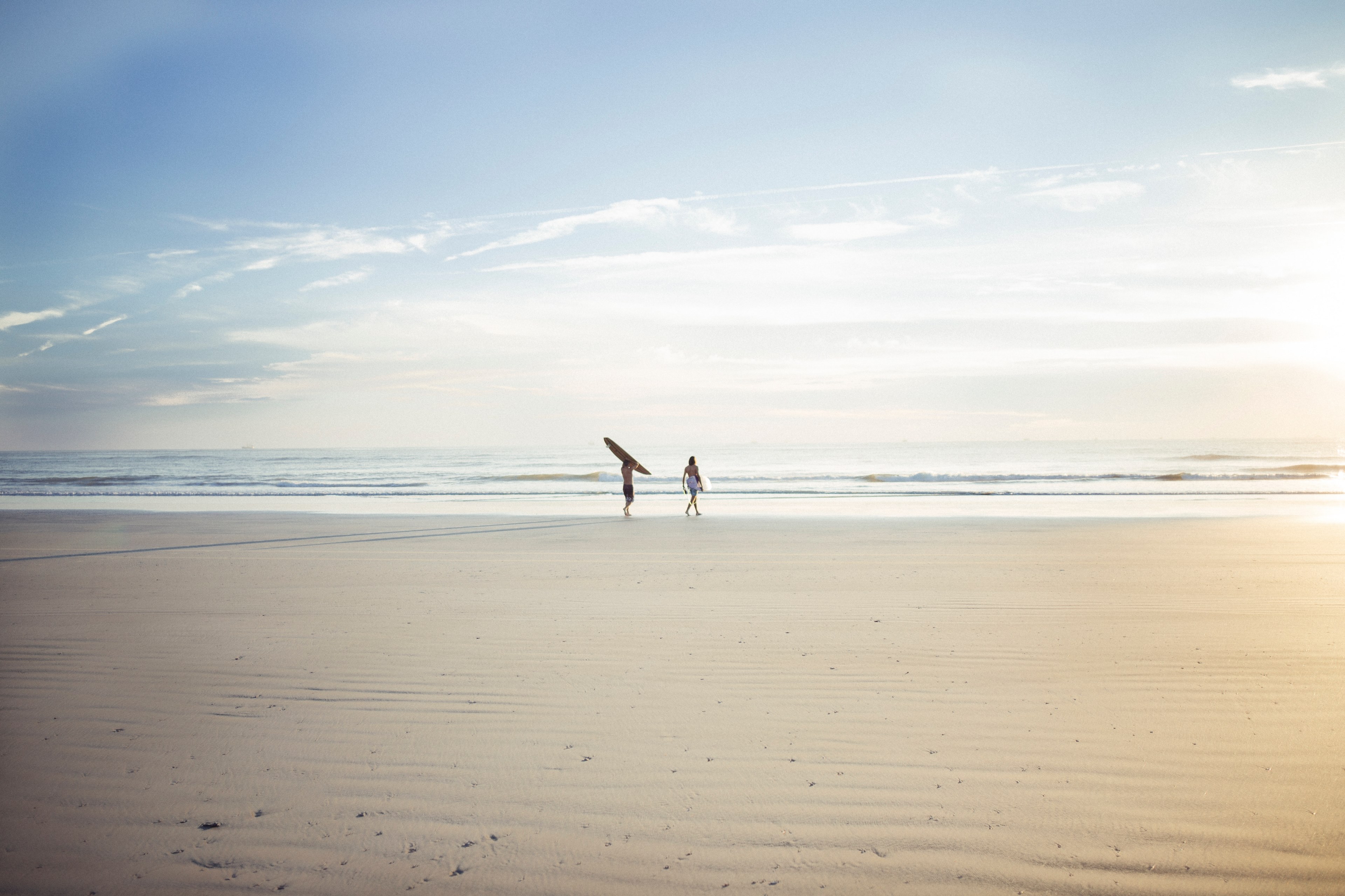 two surfers walking on the sandy beach towards the ocean, heading into the surf 4k, HD Wallpaper