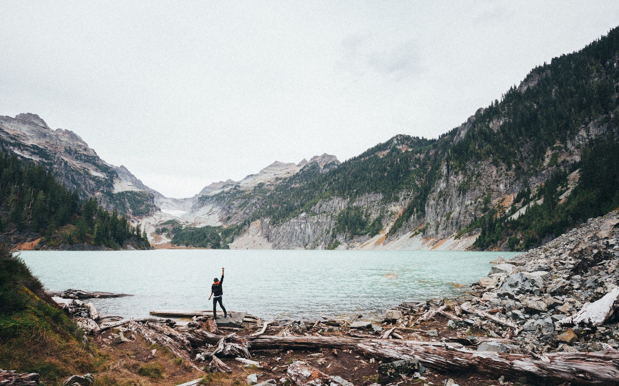 a woman raising her hand in a triumphant gesture on the edge of a mountain lake, celebrating on the lake 4k, HD Wallpaper