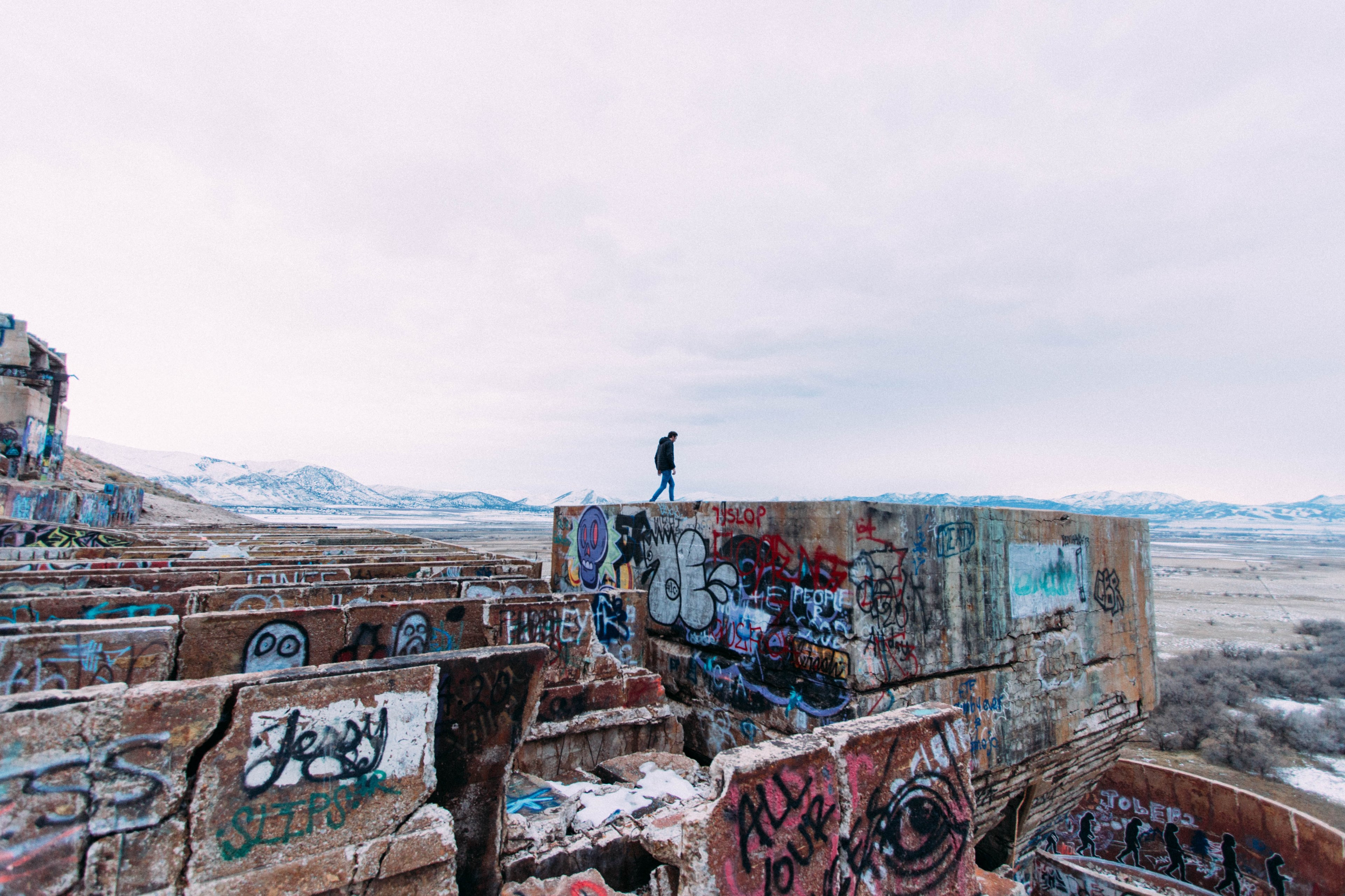 person walking on concrete structure covered in graffiti in isolated region, graffiti covered architecture 4k, HD Wallpaper